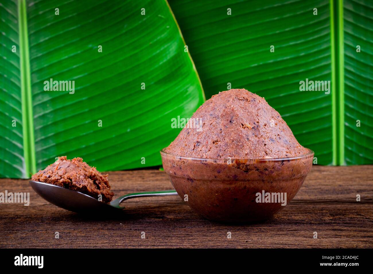 pasta di gamberetti ( kapi ) su fondo di legno marrone e foglia di banana Foto Stock