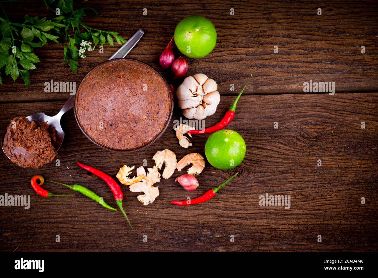 pasta di gamberi organica ( kapi ) e ingrediente tailandese su fondo di tessitura di legno marrone. Vista dall'alto Foto Stock