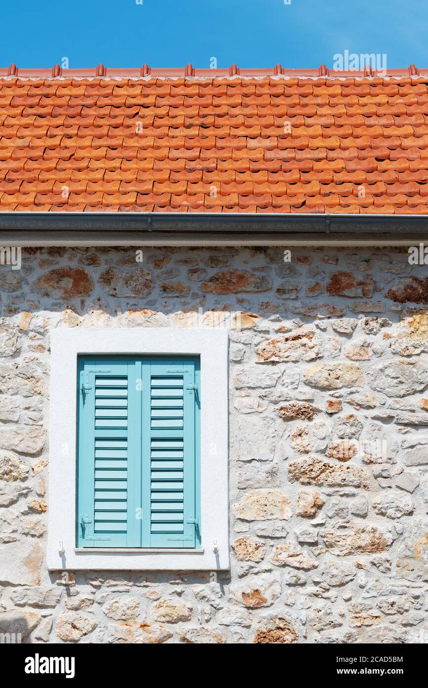 Finestra chiusa con persiane turchesi su una vecchia casa mediterranea con muro in pietra. Architettura, viaggi, turismo e vacanze. Foto Stock