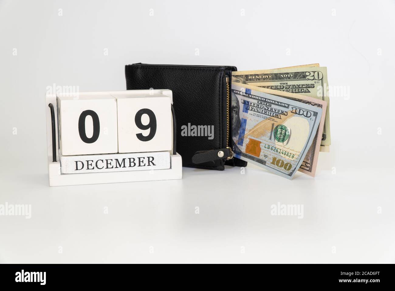 calendario e portafoglio con denaro. Cubo di legno fatto a mano con data mese e giorno. Foto Stock