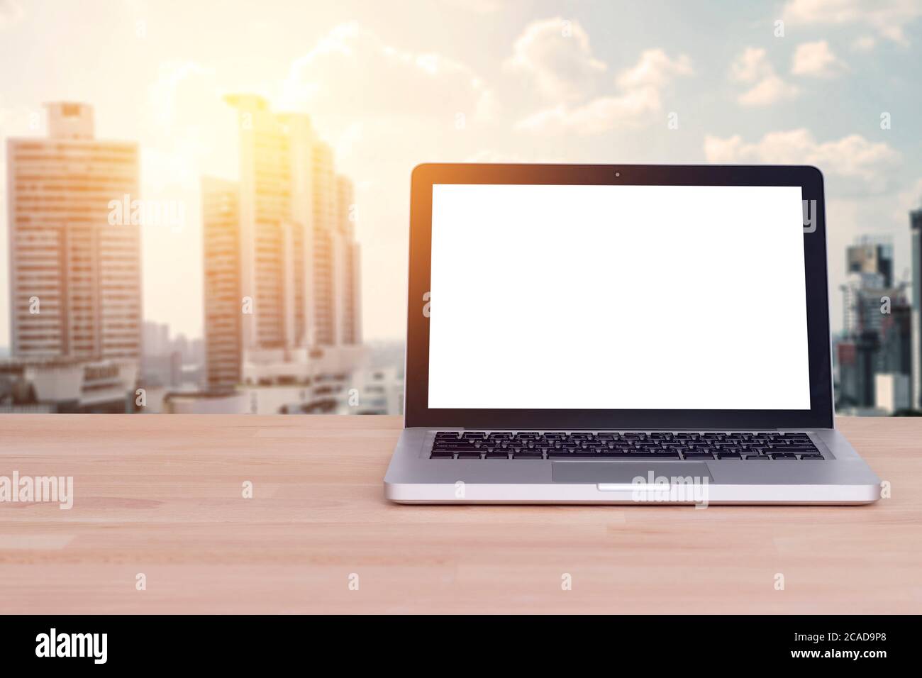Tecnologia per un concetto di business confortevole: Schermo bianco vuoto su notebook, laptop con blur building e sfondo urbano, effetto film. Foto Stock