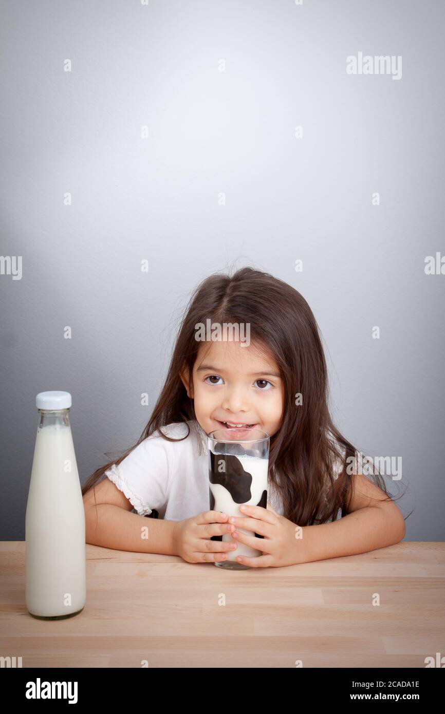 Adorabile bambina che tiene un bicchiere di latte e di latte Foto Stock