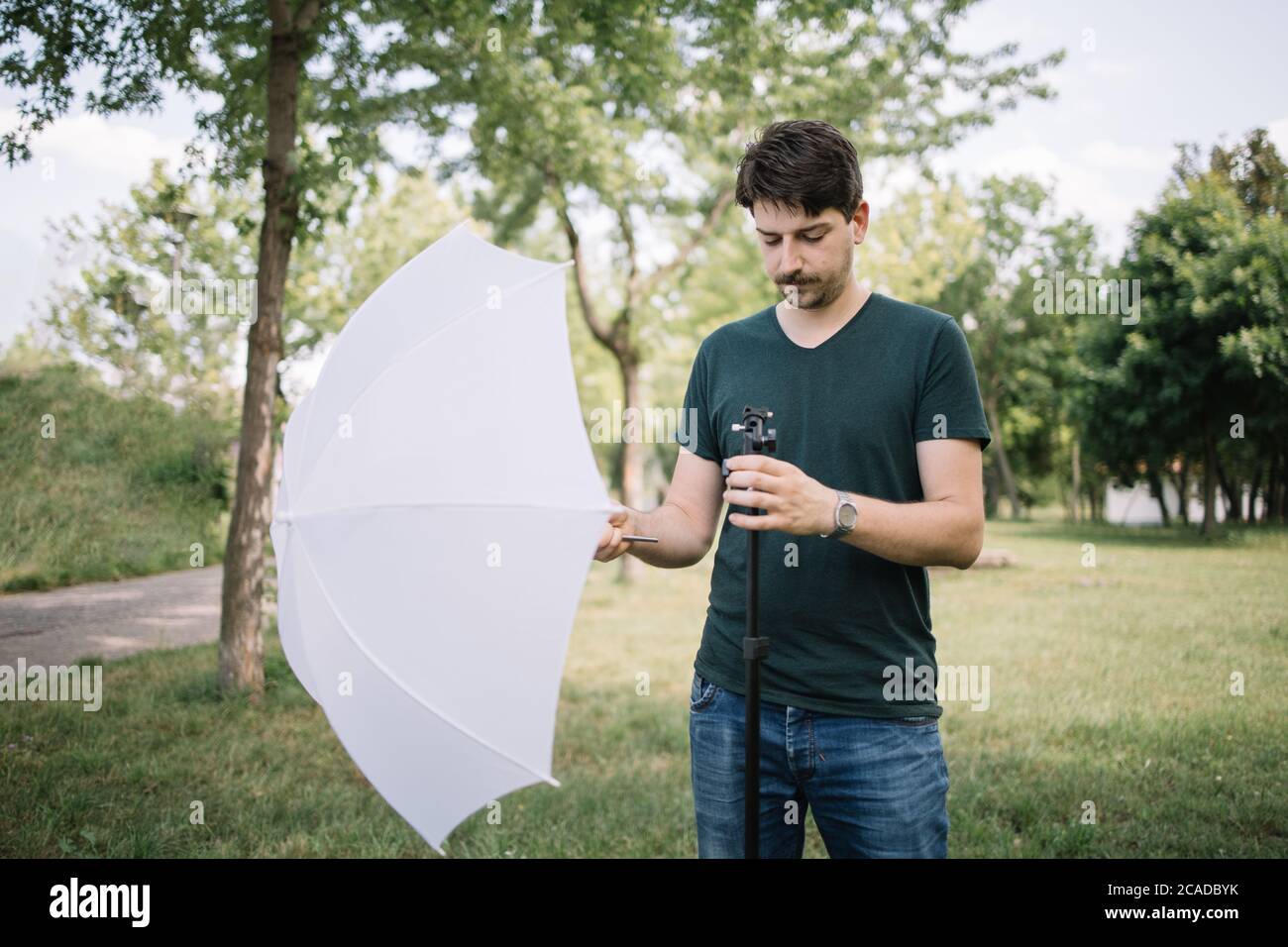 Fotografo posizionamento ombrello diffusore per la realizzazione di studio fotografico esterno Foto Stock