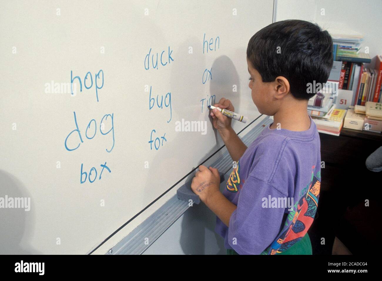 Ragazzo ispanico che impara l'ortografia usando una lavagna a secco nella sua classe nella scuola privata. ©Bob Daemmrich Foto Stock