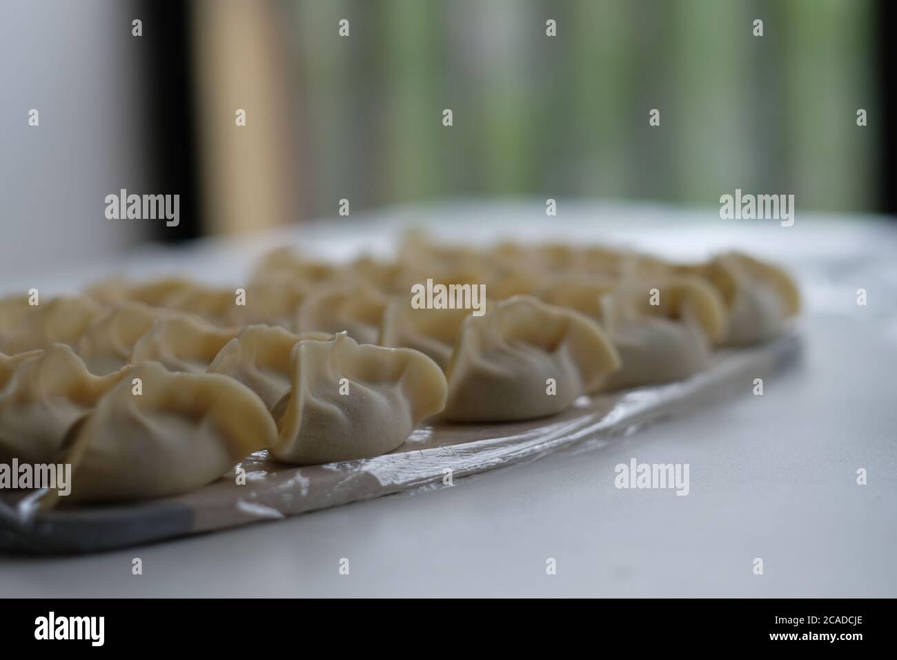 Primo piano molti gnocchi grezzi messi in buon ordine su tavola bianca. Sfocatura dello sfondo. Cucina cinese tradizionale. Foto Stock