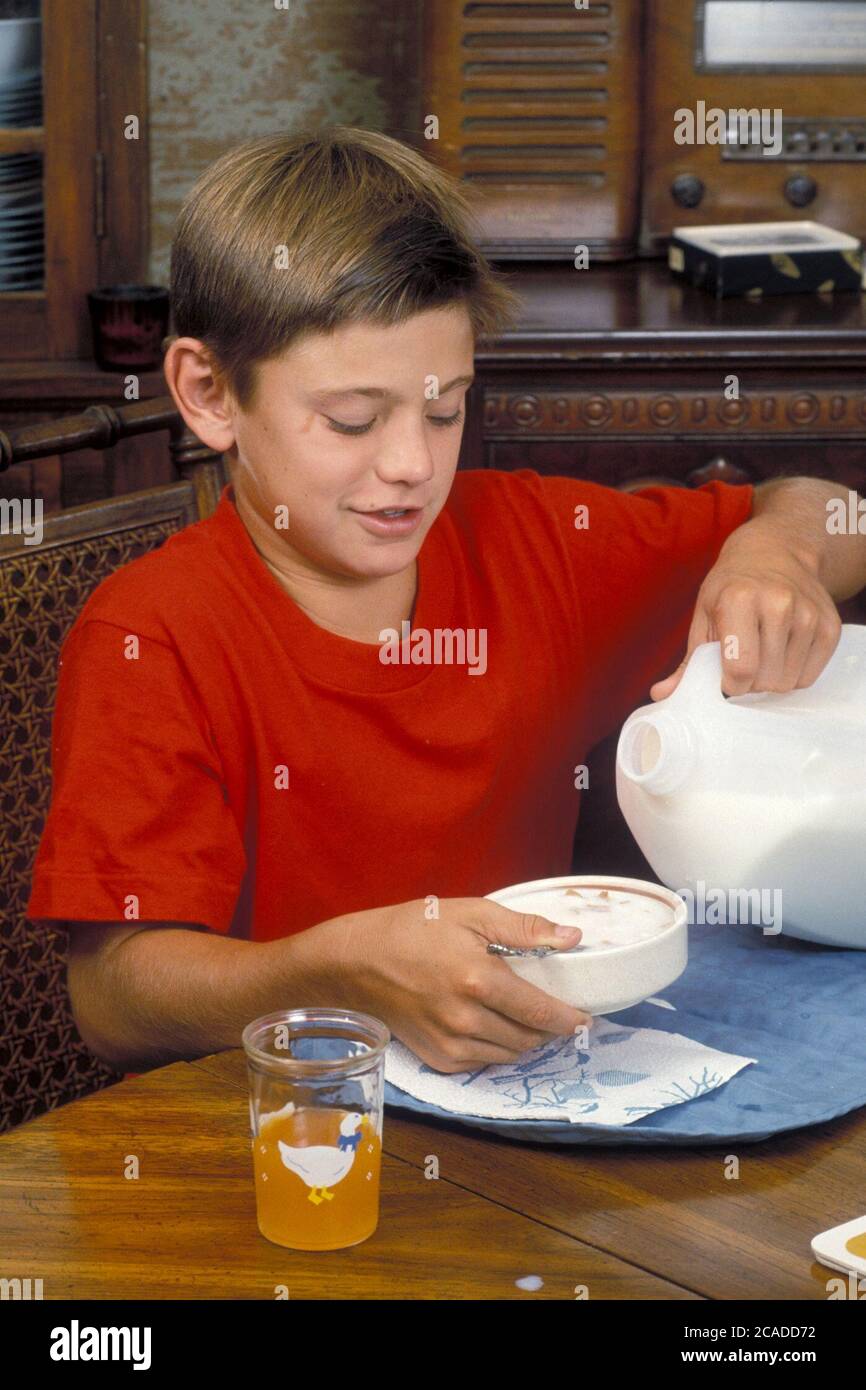 Austin Texas USA: Un anglo di 11 anni che versa latte nel cestino dei cereali per la colazione a casa. Versione modello ©Bob Daemmrich Foto Stock