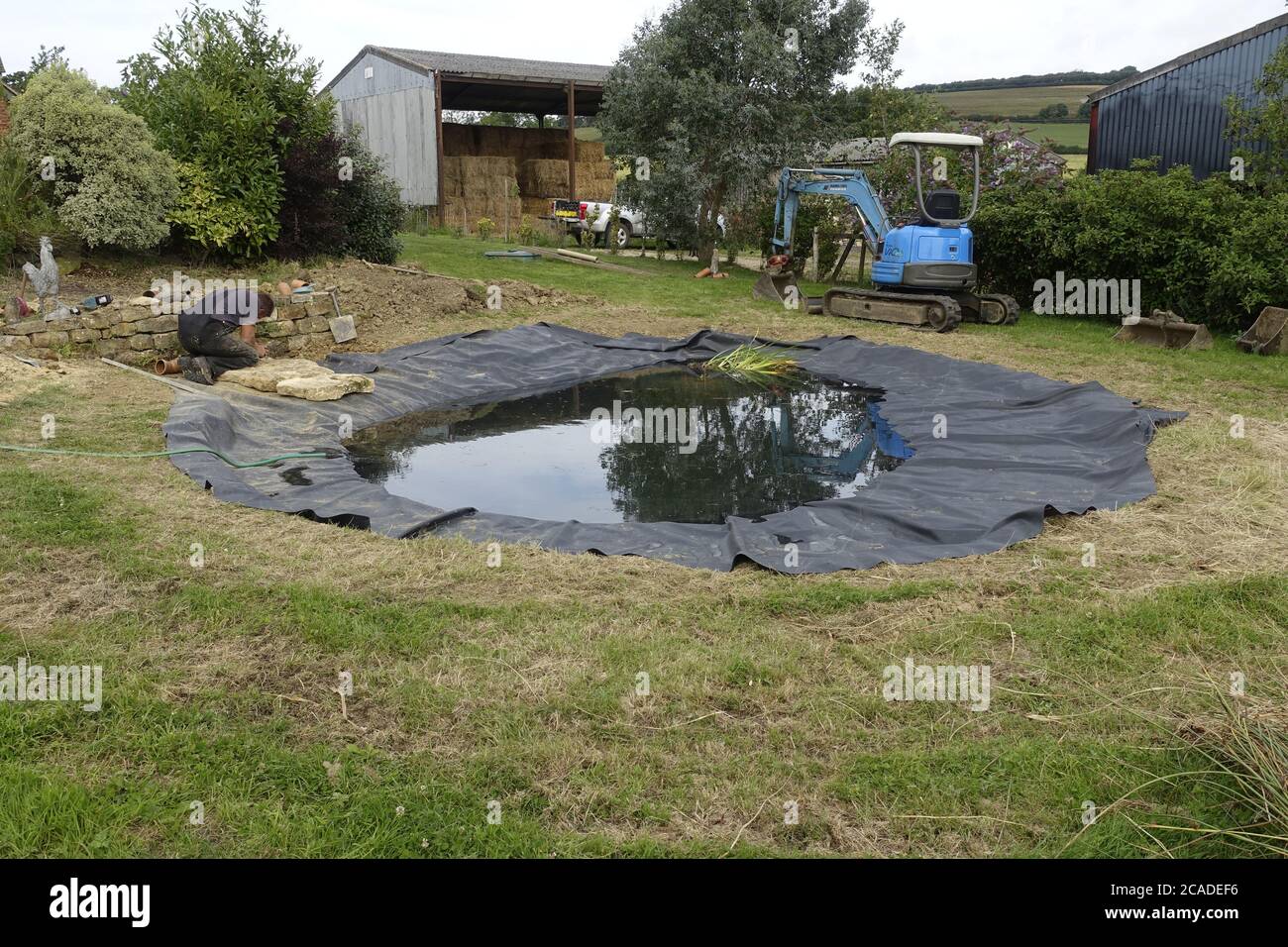 Costruzione di laghetti da giardino con liner in gomma EPDM, Cpotswolds, Regno Unito Foto Stock
