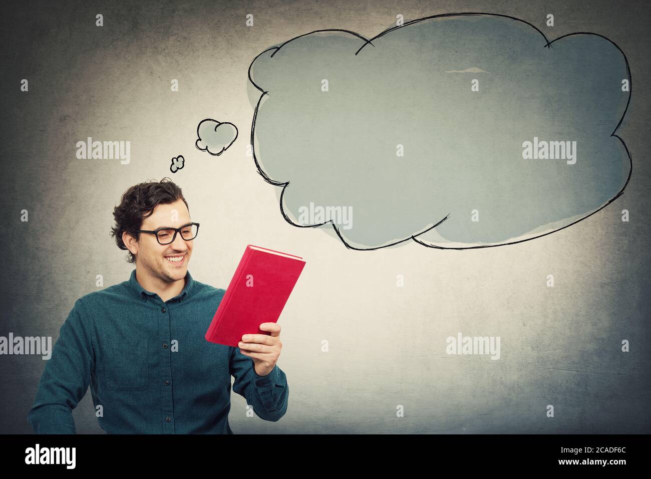 Felice giovane uomo, allievo ragazzo, tenendo un interessante libro rosso, leggendo il titolo del libro di testo. Concetto di istruzione, processo di apprendimento. Tipo scegliere che cosa rea Foto Stock