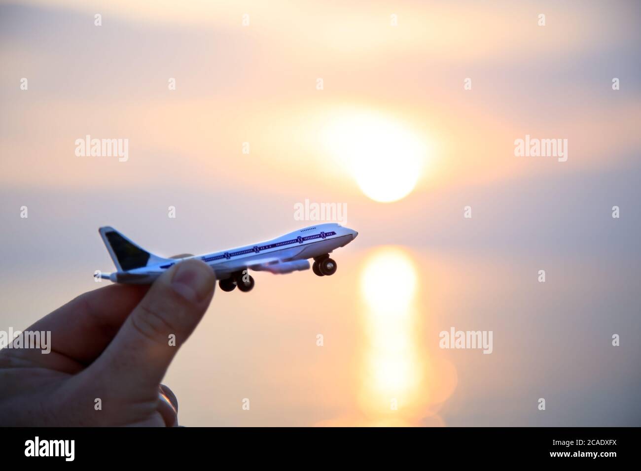 aereo giocattolo in mano sullo sfondo di un bellissimo tramonto sul mare. Silhouette. Spazio di copia Foto Stock