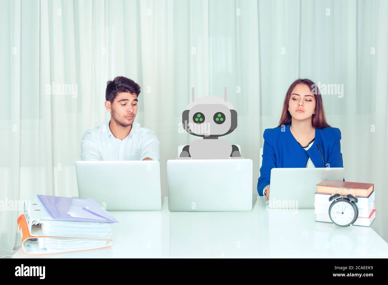 I dipendenti aziendali di giovani uomini e donne con computer portatili sono gelosi di nuovi e innovativi colleghi robot che lavorano seduti al tavolo, invidia circa h. Foto Stock