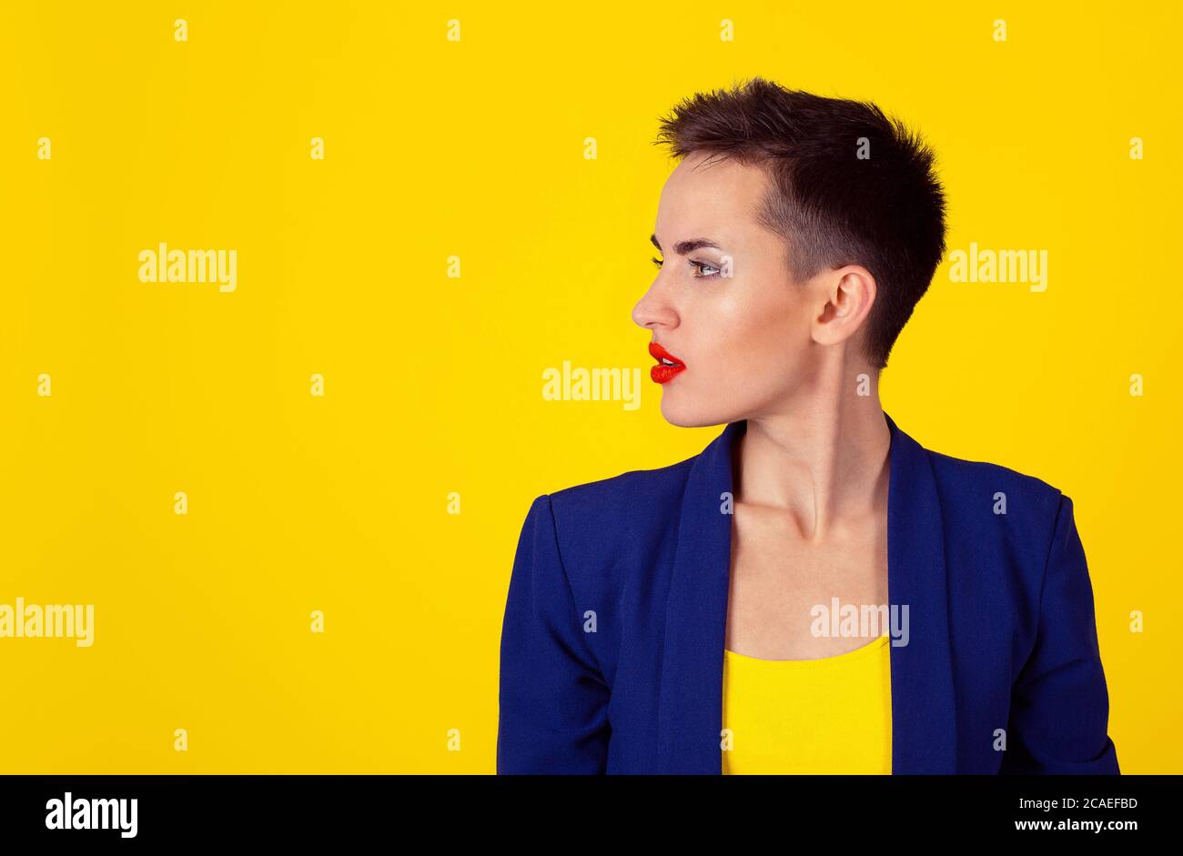 Ritratto bella donna nel profilo laterale pensando di sinistra grave isolato su sfondo giallo con spazio di copia. Modello in camicia gialla, blu s. Foto Stock