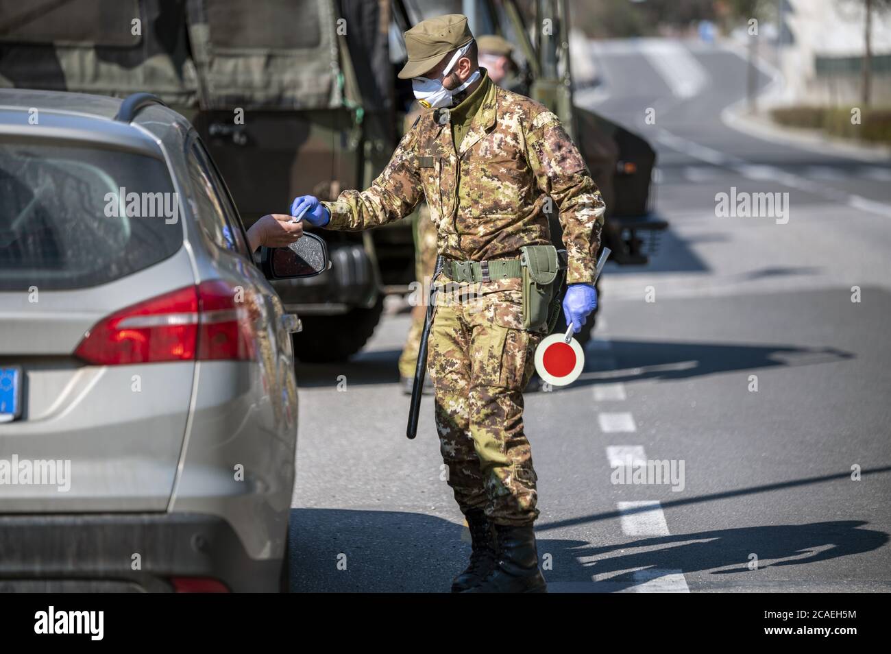 Soldati militari controllano la strada. Pattuglia di sicurezza con maschere e guanti per monitorare gli automobilisti che passano. Controllo giornaliero su strada per il Covid-19. Foto Stock