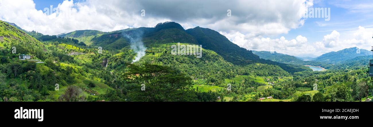 Paesaggio panoramico dello Sri Lanka. Cascata in montagna e piantagione di tè. Fumo dietro gli alberi. Foto Stock
