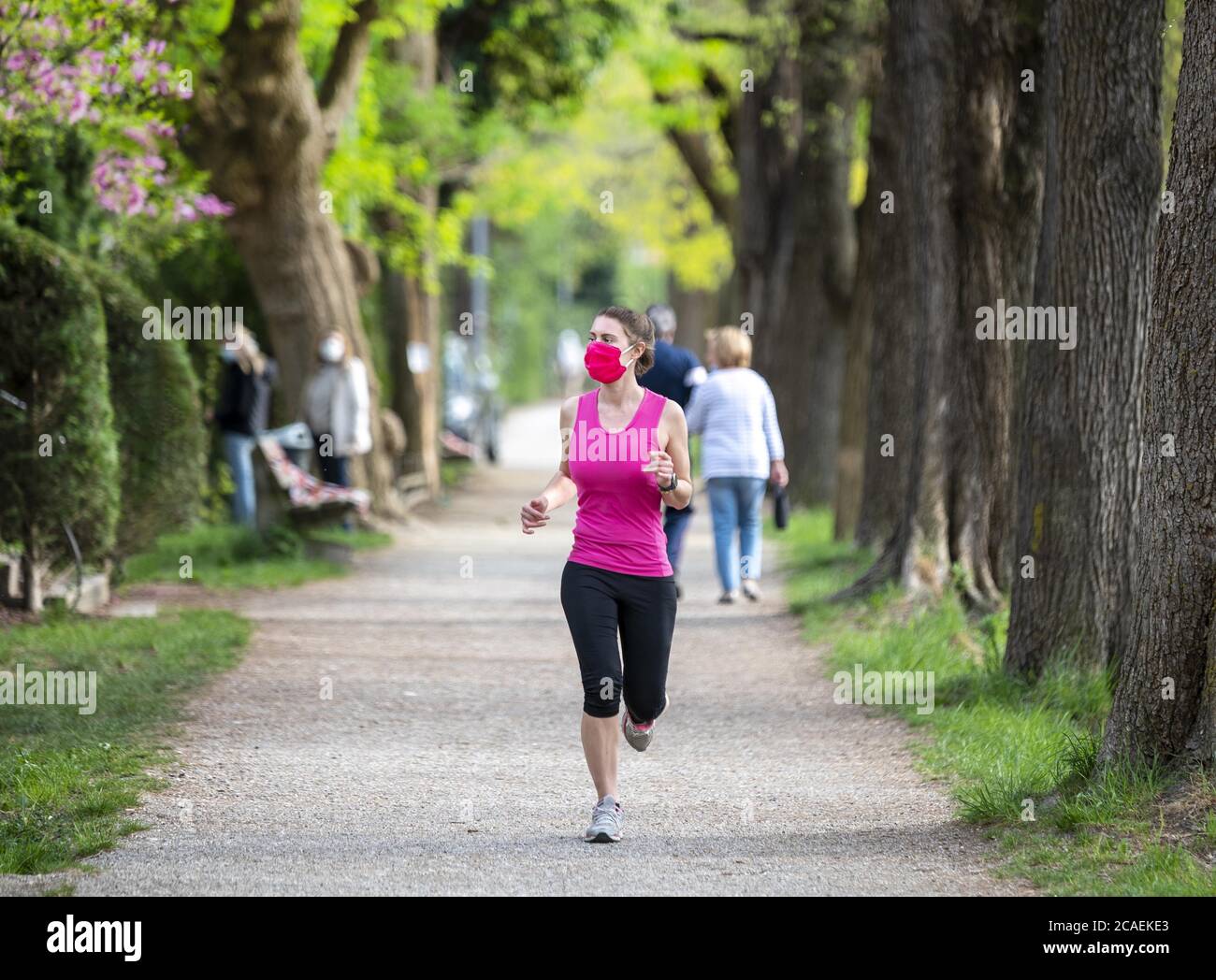 Mantenersi in forma durante il Coronavirus. Una donna sportiva sta facendo jogging all'aperto, ha una maschera protettiva sul viso. In esecuzione nei giorni del Covid-19. Foto Stock