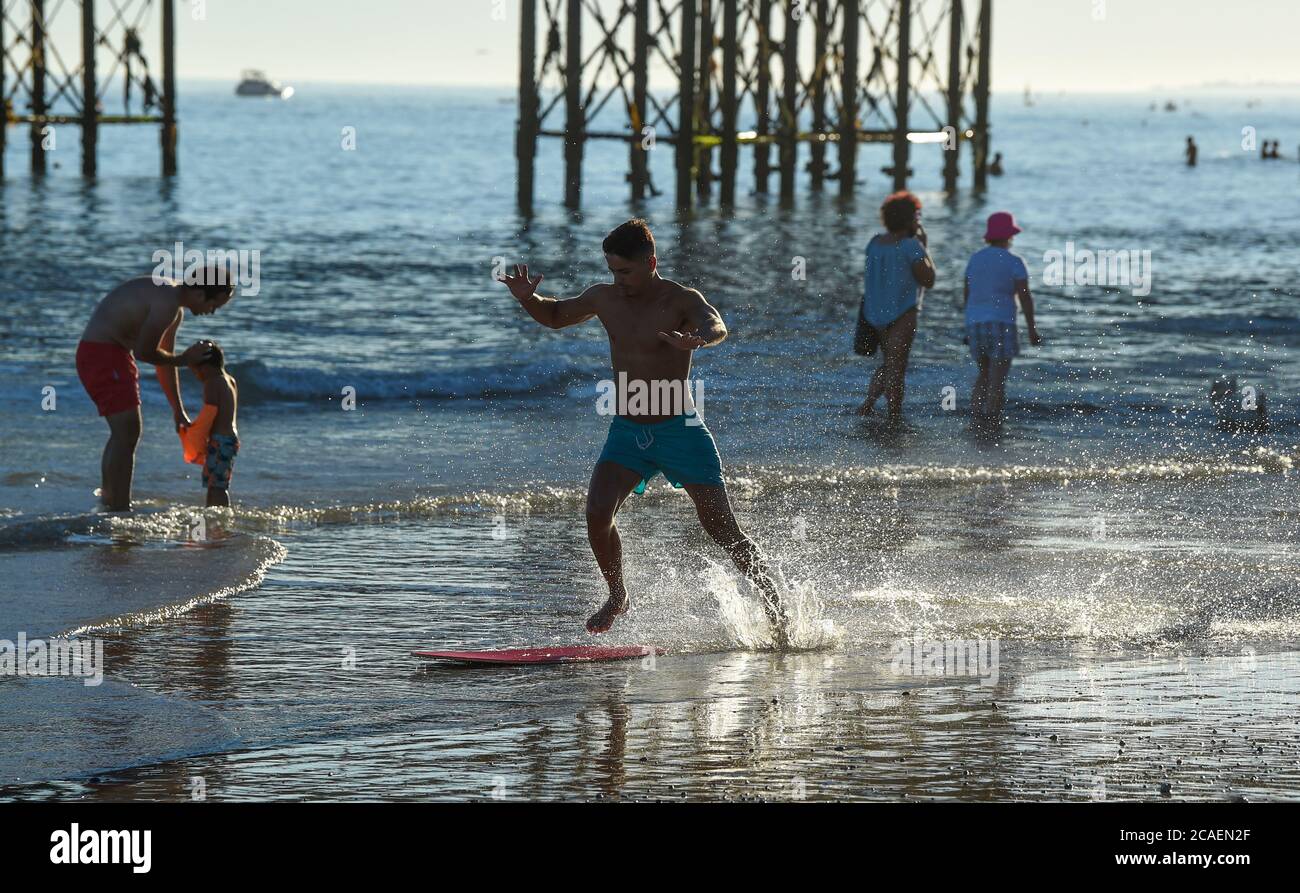 Brighton UK 6 agosto 2020 - questo giovane uomo ama scivolare in mare sulla spiaggia di Brighton in una bella serata di sole come si prevede che le temperature raggiungeranno di nuovo al di sopra di 30 gradi nel Sud Est di domani : Credit Simon Dack / Alamy Live News Foto Stock