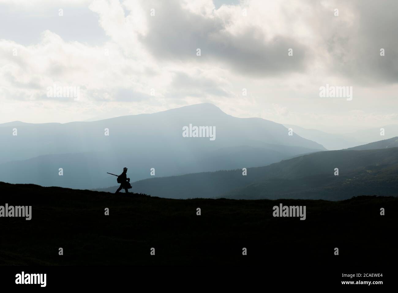 Una silhouette di un fotografo con un treppiede sullo sfondo delle maestose montagne. Fotografia di paesaggio Foto Stock