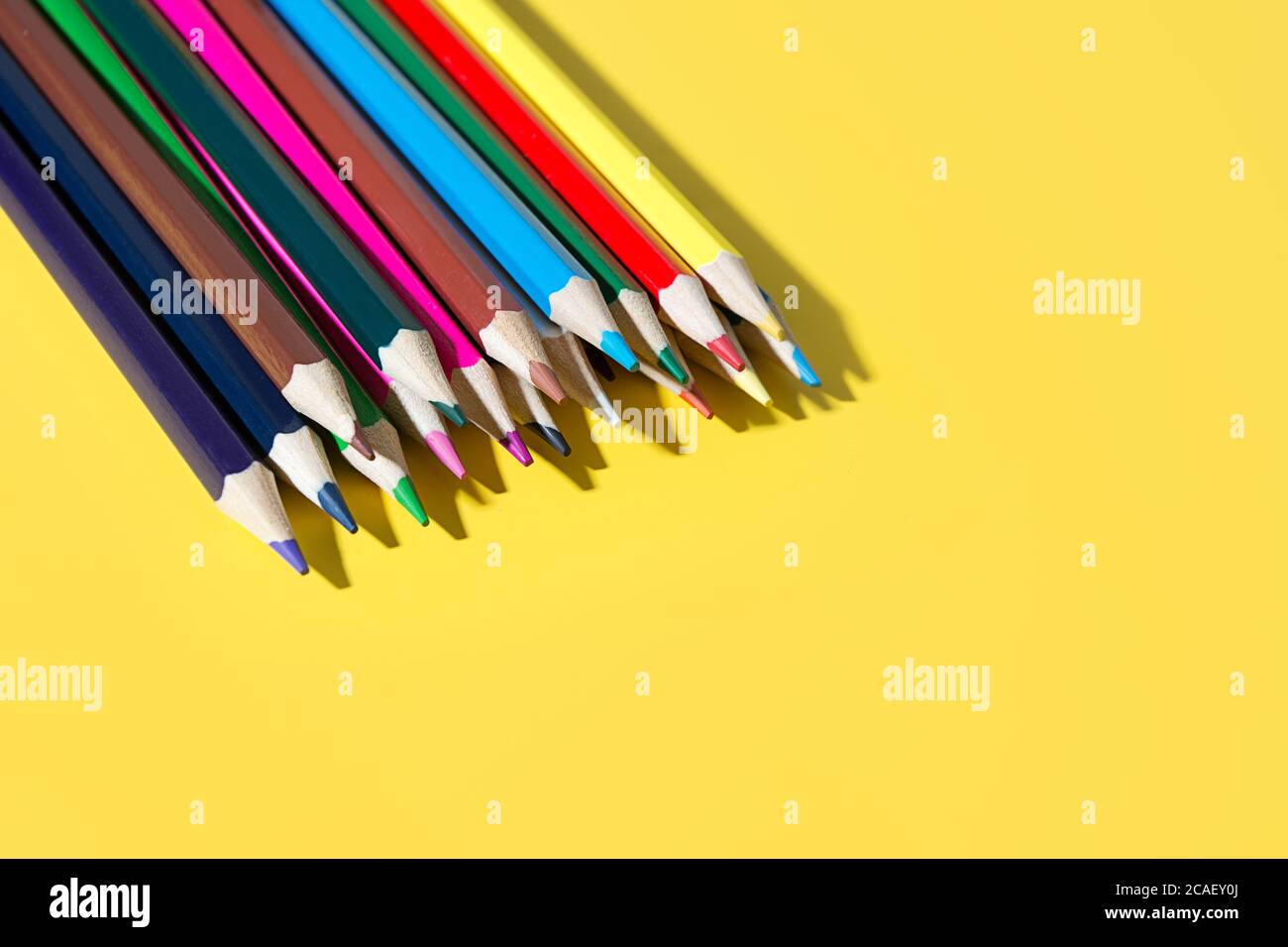 Matite colorate per disegnare e studiare a scuola. Forniture scolastiche luminose su sfondo giallo. Foto Stock