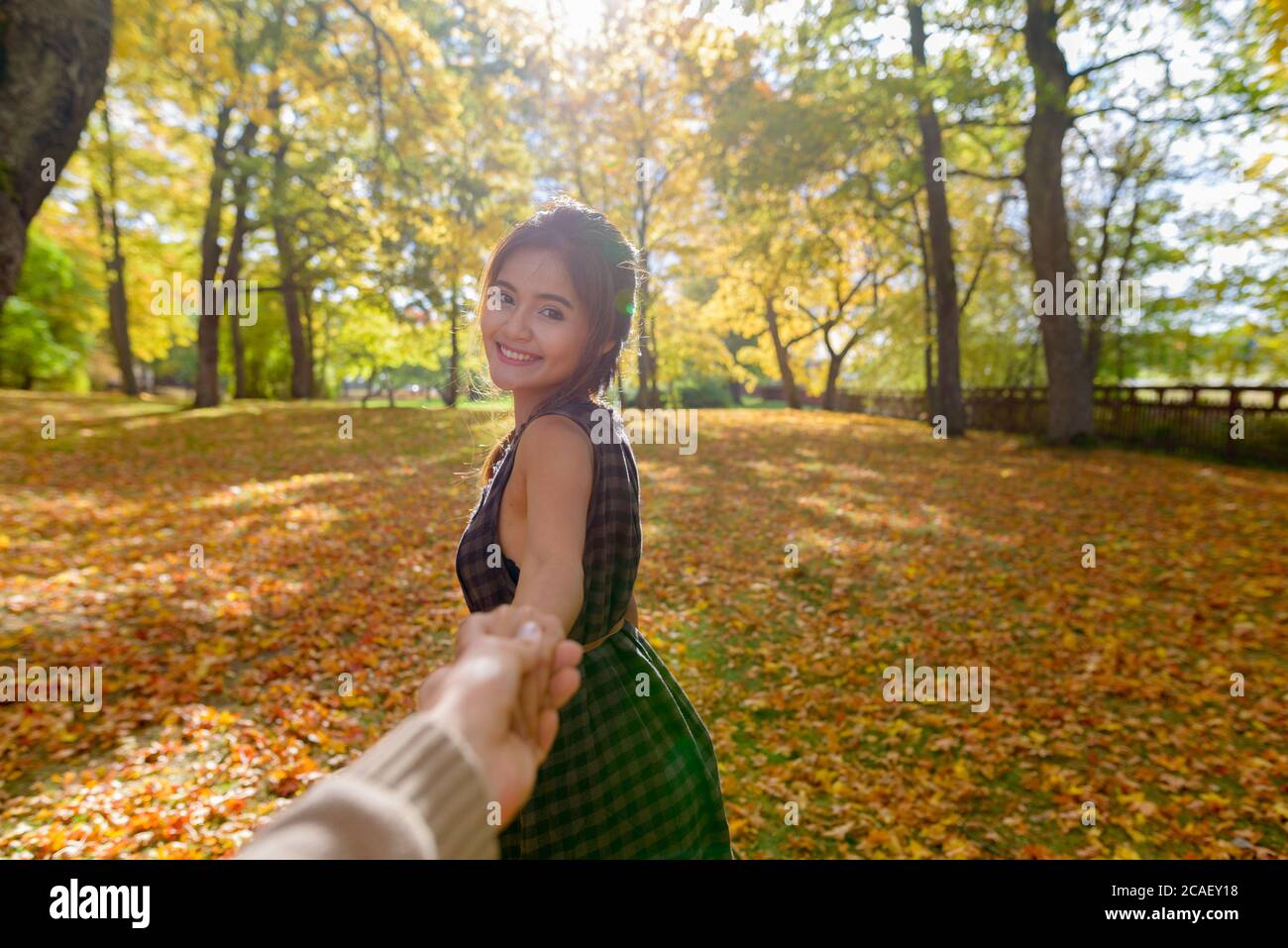 Giovane donna asiatica felice sorridente mentre guida l'uomo nella foresta tenendo le mani Foto Stock