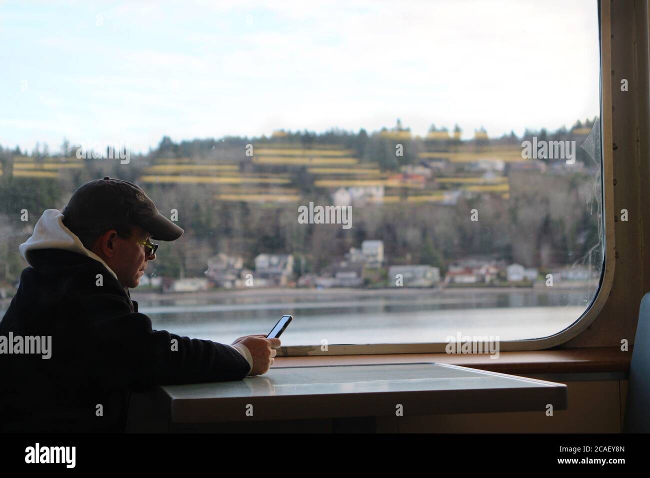 Il passeggero che sta testando e guardando il suo telefono cellulare mentre si fa un giro in traghetto a Seattle. Foto Stock