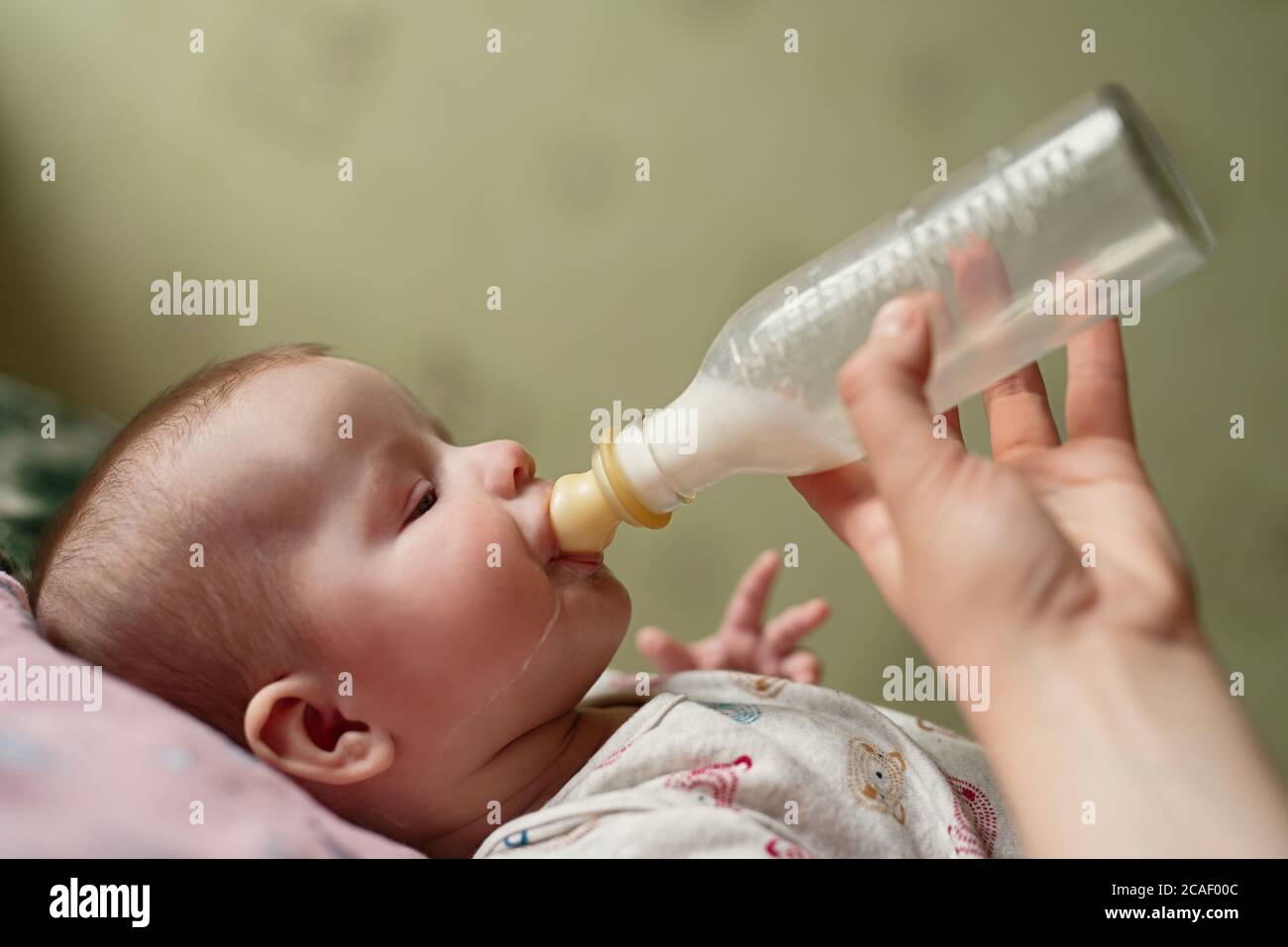 il neonato mangia il latte dal biberon, gocce di cibo scendono giù guancia,  papà dà il miscuglio del bambino Foto stock - Alamy