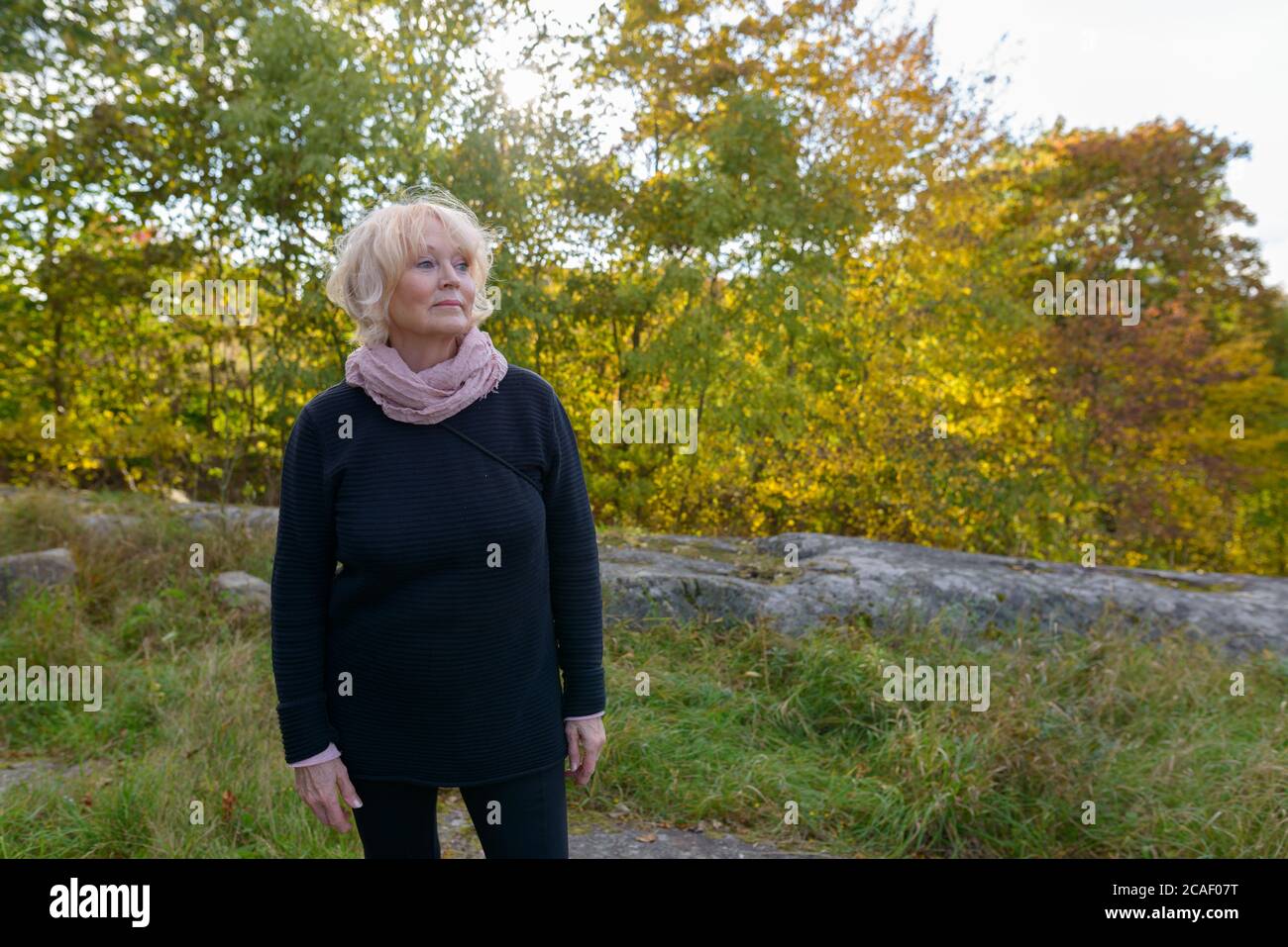 Donna anziana che guarda la distanza di fronte a uno splendido paesaggio in montagna Foto Stock