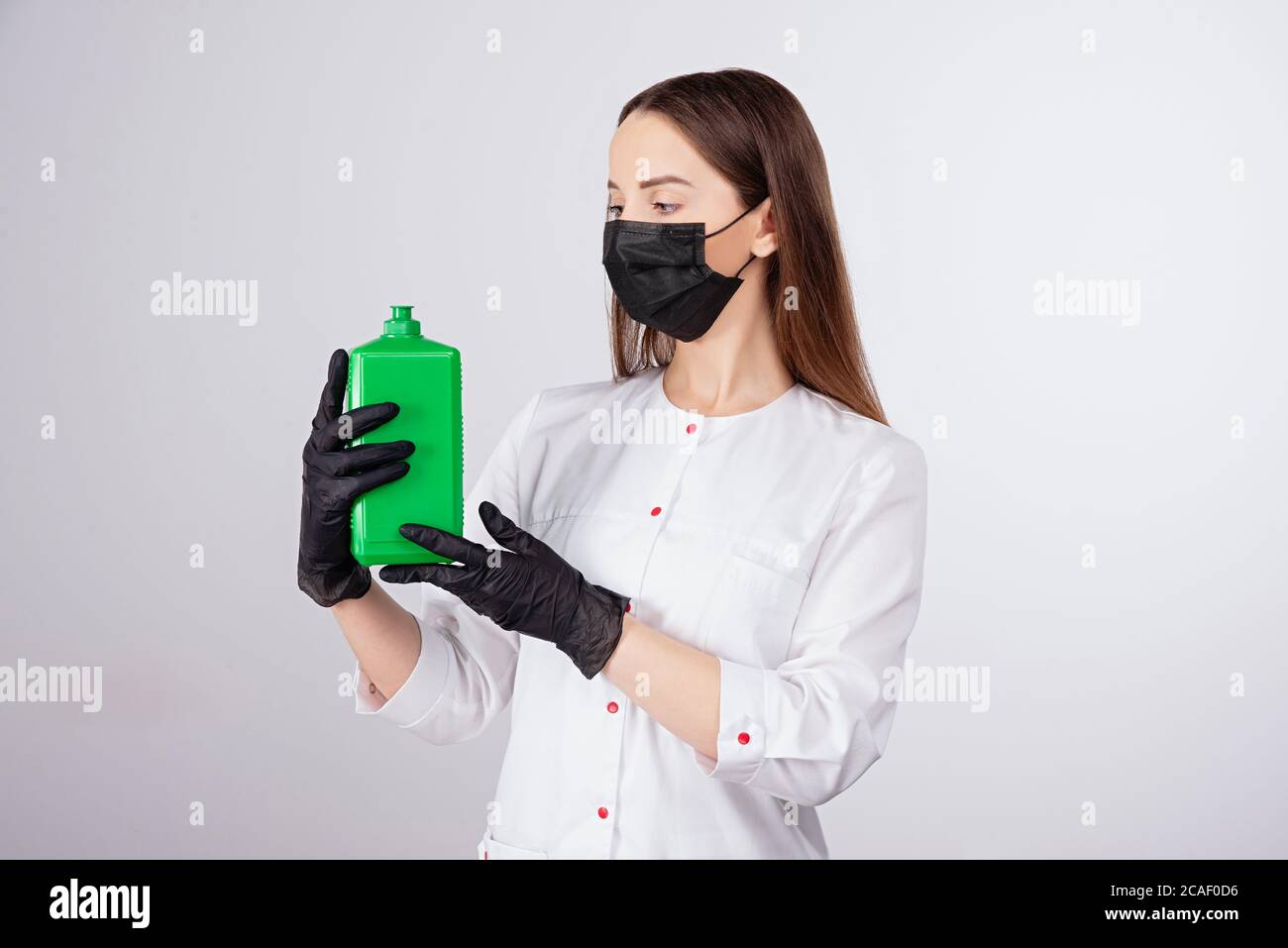 il medico tiene la soluzione disinfettante nelle sue mani, la protezione contro il covid-19 coronavirus, la ragazza in guanti neri e la maschera guarda bottiglia, disin Foto Stock