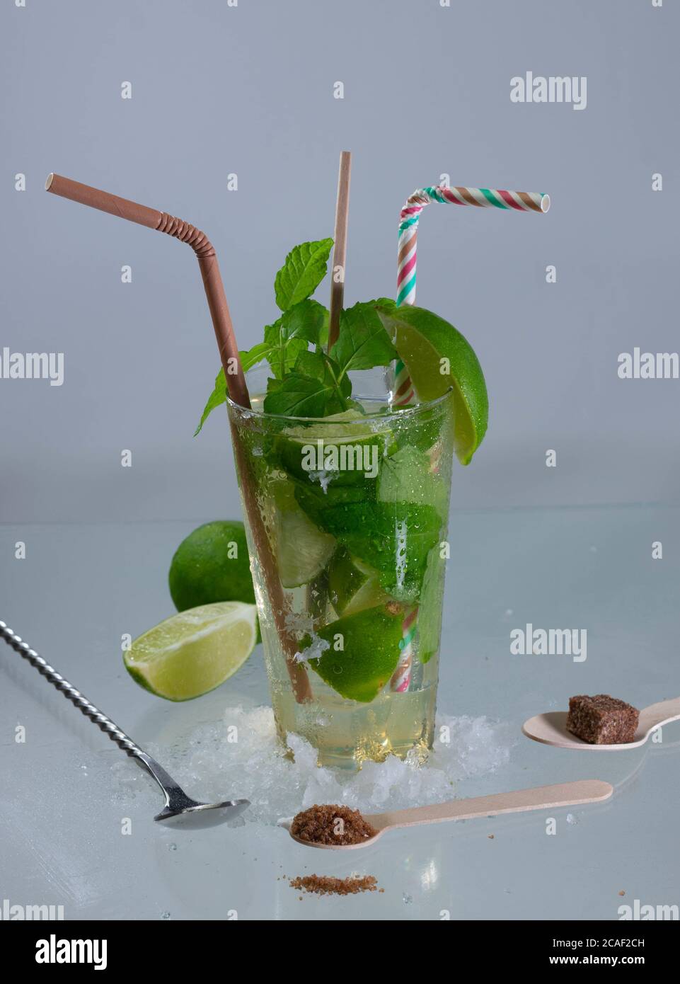 Colpo verticale di un cocktail mojito con foglie di rum, lime e menta su una superficie grigia Foto Stock
