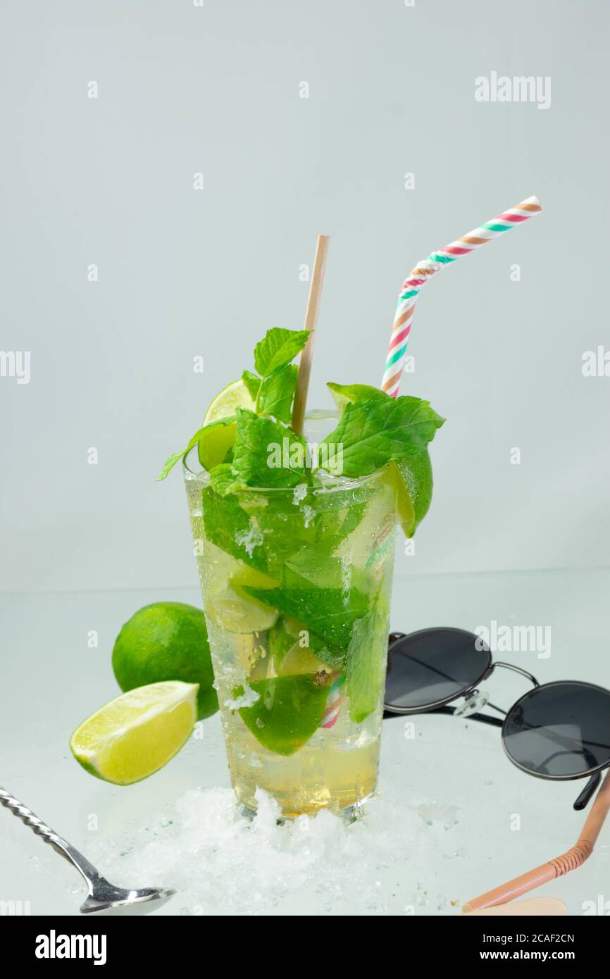 Colpo verticale di un cocktail mojito con foglie di rum, lime e menta su una superficie grigia Foto Stock