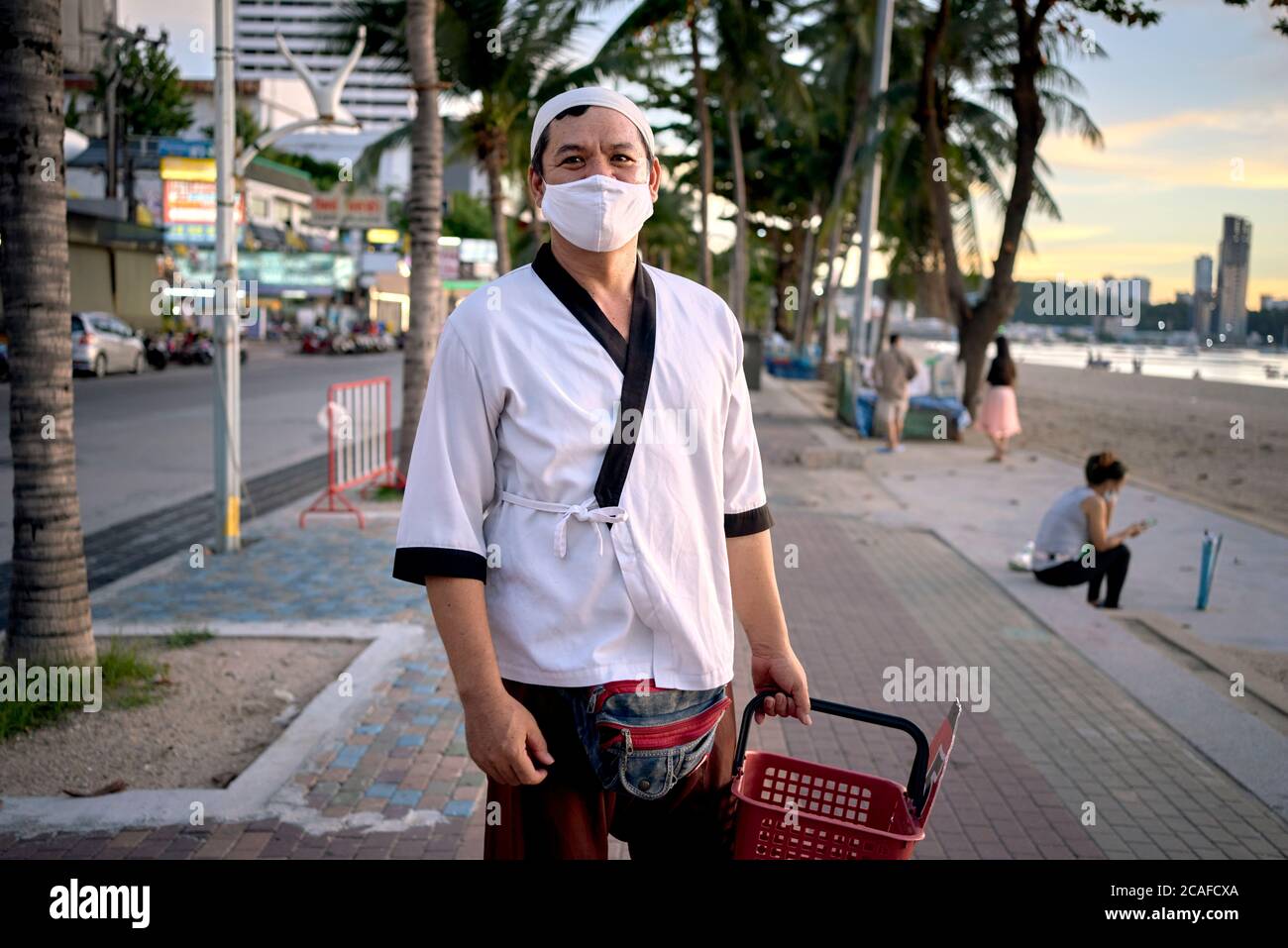 Chef di un ristorante giapponese, ancora nella sua uniforme di lavoro, che si fa strada a casa dopo il lavoro. Thailandia Sud-est asiatico Foto Stock