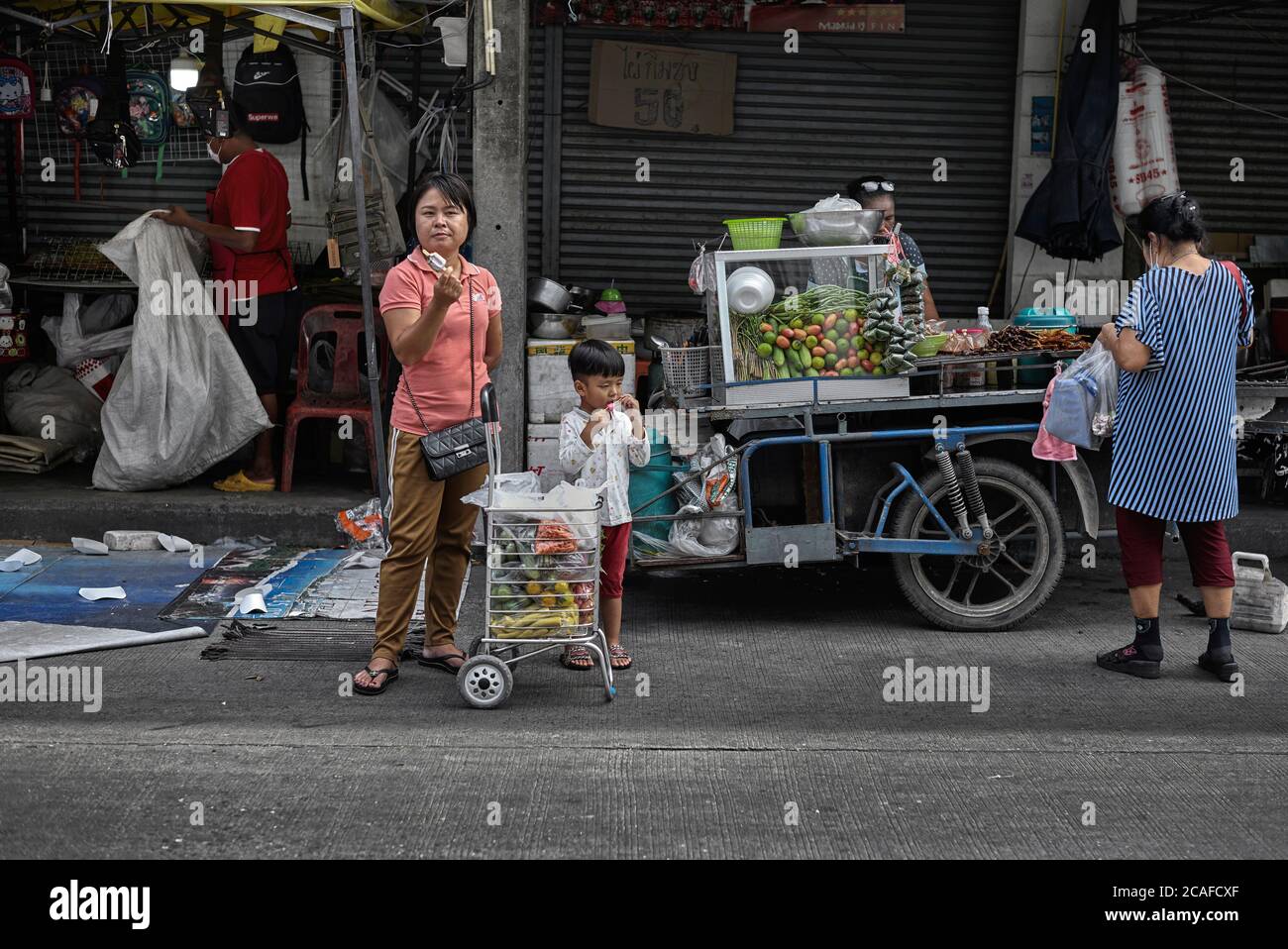 Donna cibo shopping con il suo figlio e la madre giovane a un thailand Street food cart. Sud-est asiatico Foto Stock