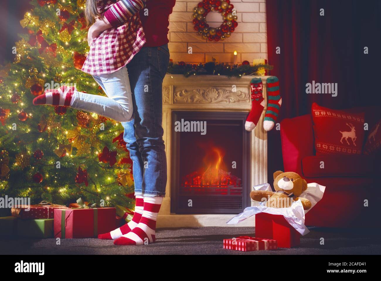 Buon Natale e buone feste! Carino bambino abbraccia un genitore e gioire nel regalo. Tradizioni di famiglia di Natale. Foto Stock