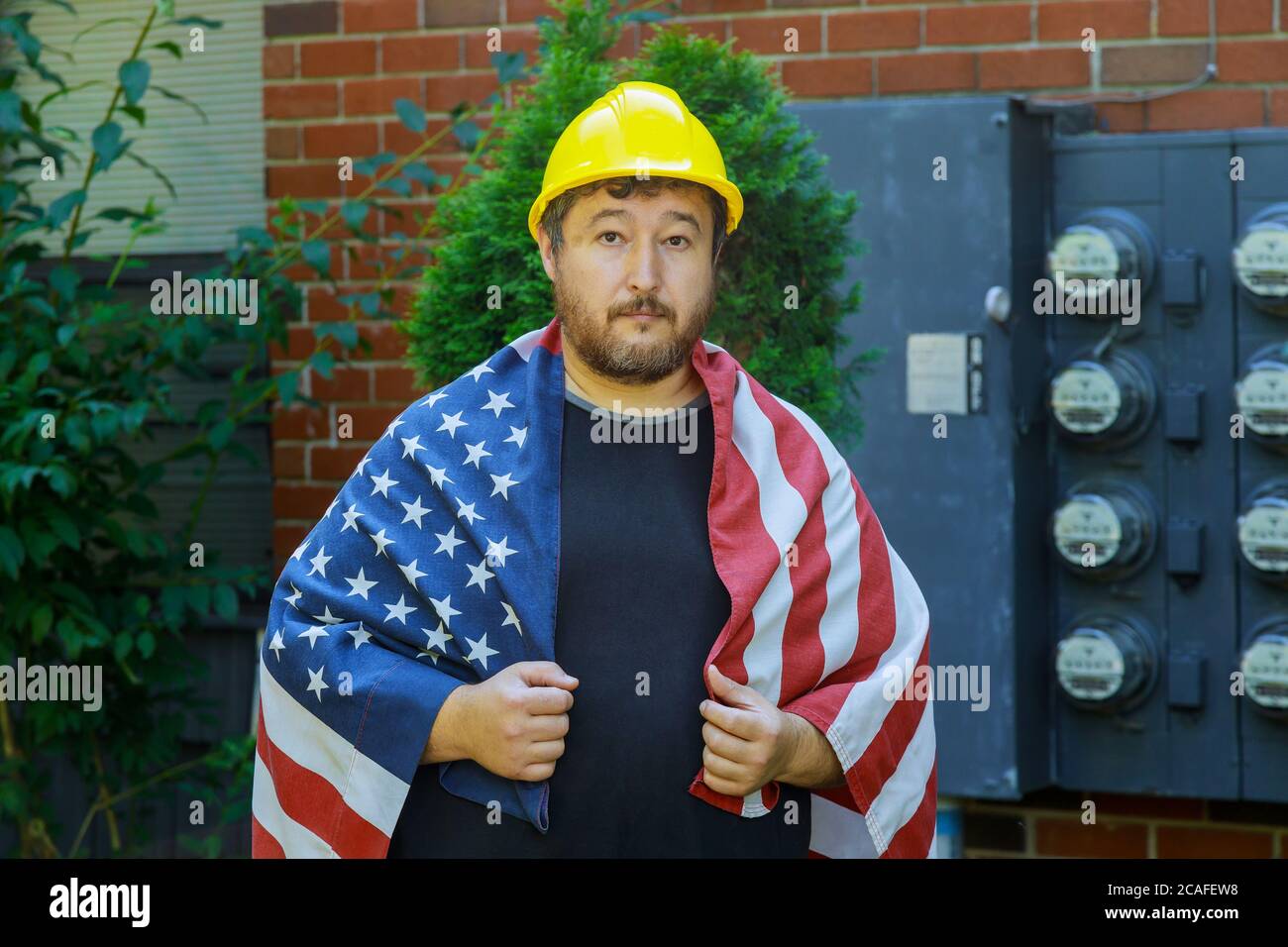 Concetto di Labor Day per persone che indossano lavoratori in un casco giallo con una bandiera americana Foto Stock