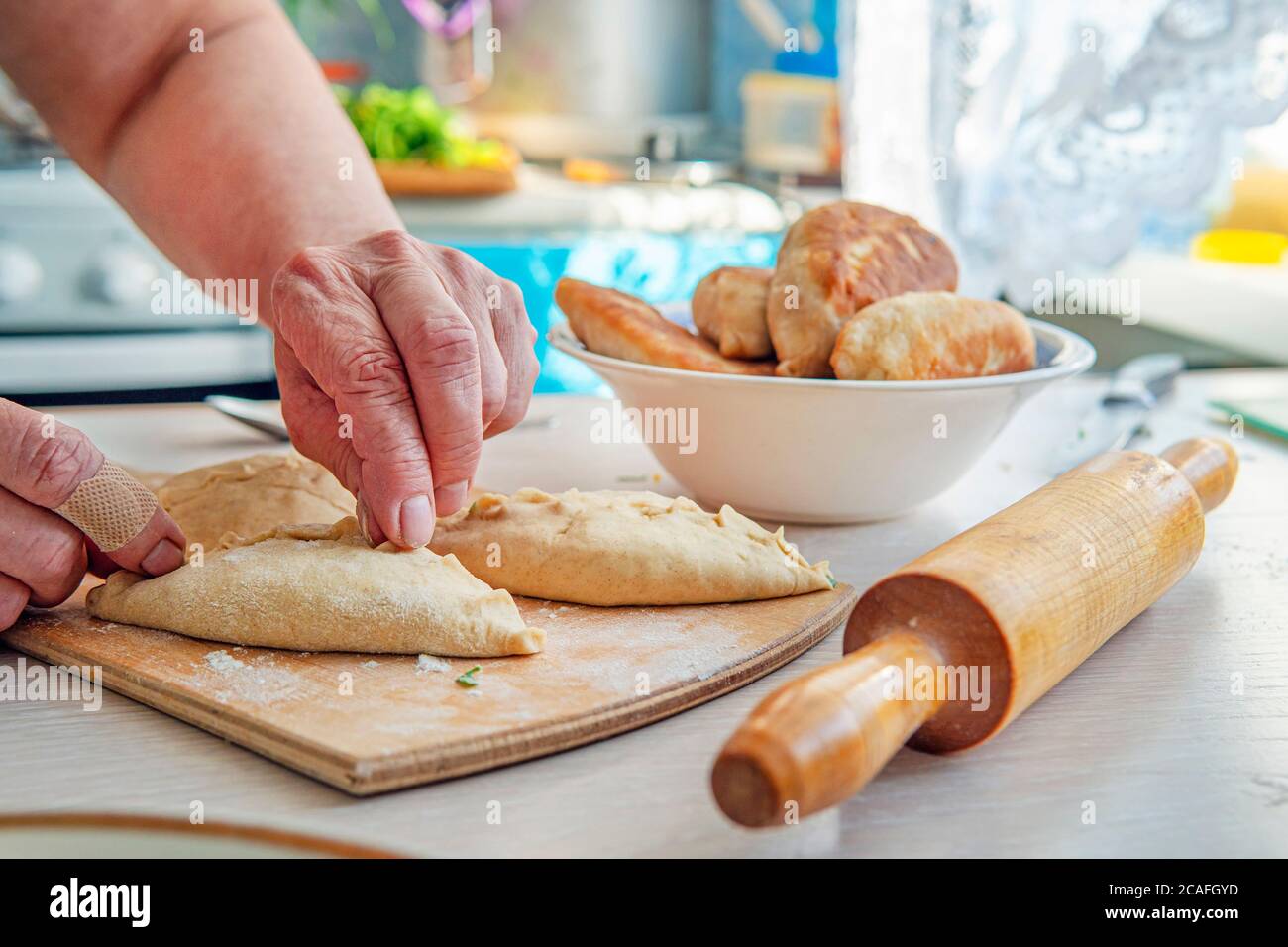 Nonna è in cucina torte da forno. Donna panettiere cottura pane, primo piano su tavolo di legno. Concetto di cottura, prodotti di pasticceria, cucina con amore Foto Stock