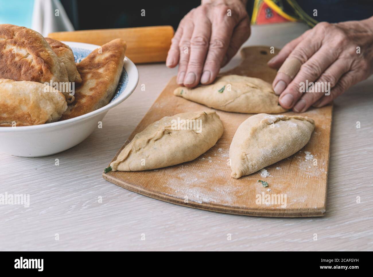 Nonna cuochi torte. Home il cibo cotto. omemade dolci di pasta in le mani delle donne. Il processo per la fabbricazione di pasta di torta a mano Foto Stock