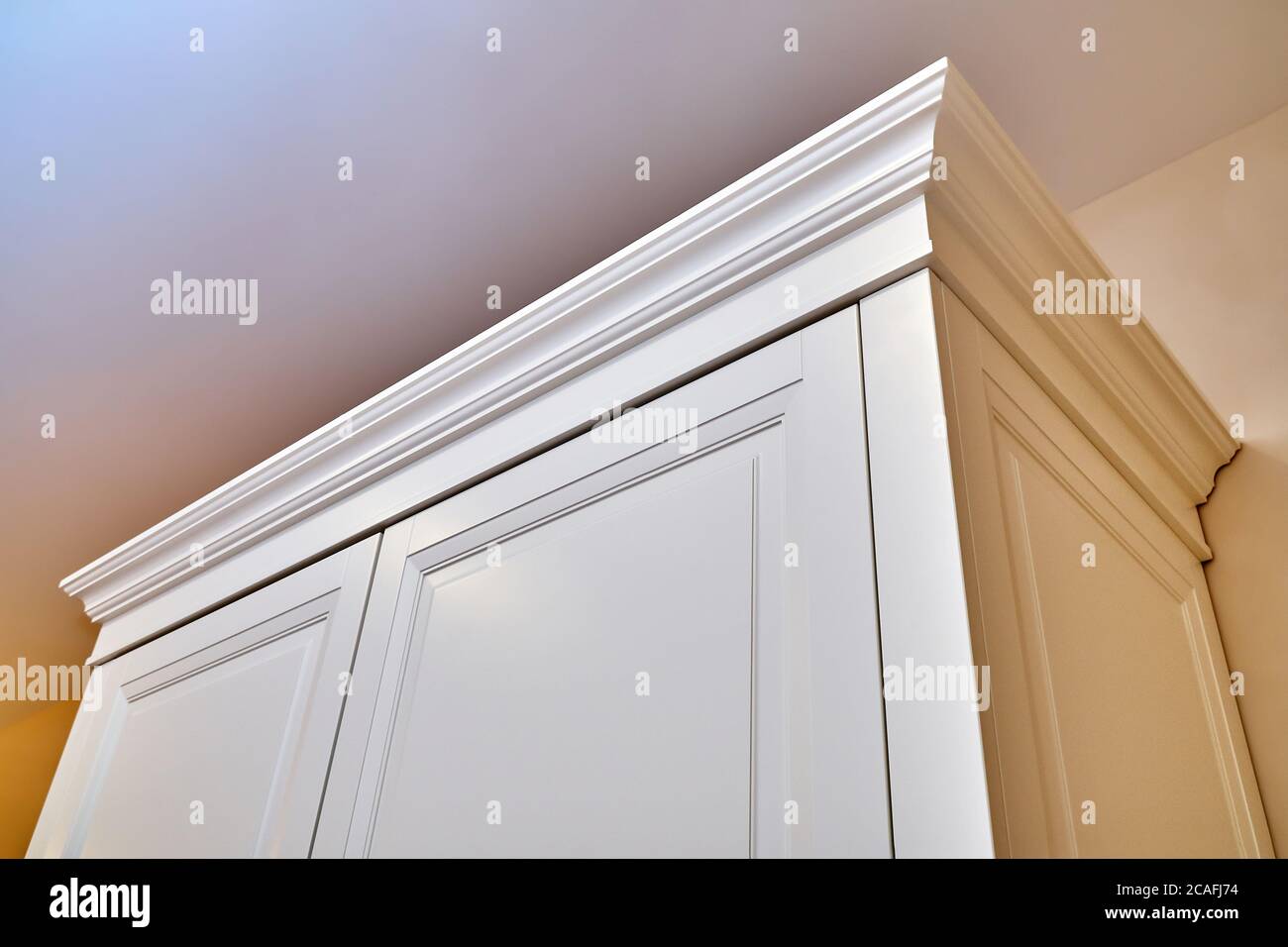 guardaroba classico. Armadio con modanatura a corona. Frammento della parte superiore del cabinet. Primo piano arredamento classico. Produzione di mobili Foto Stock guardaroba classico. Armadio con modanatura a corona. Frammento della parte superiore del cabinet. Primo piano arredamento classico. Produzione di mobili Foto Stock