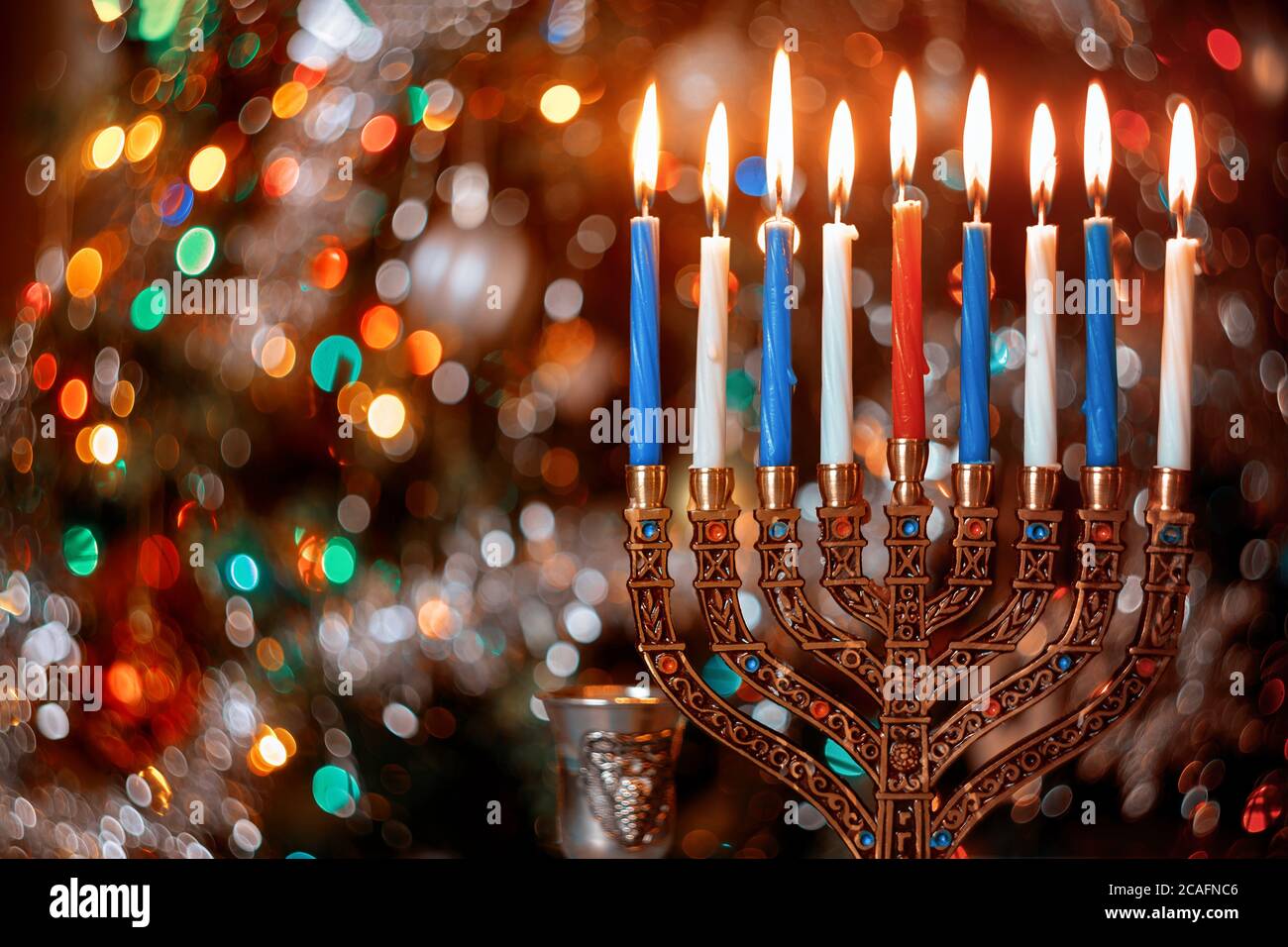 Candele brucianti con menorah per Hanukkah su sfocare colore luci di sfondo. Festa ebraica Foto Stock