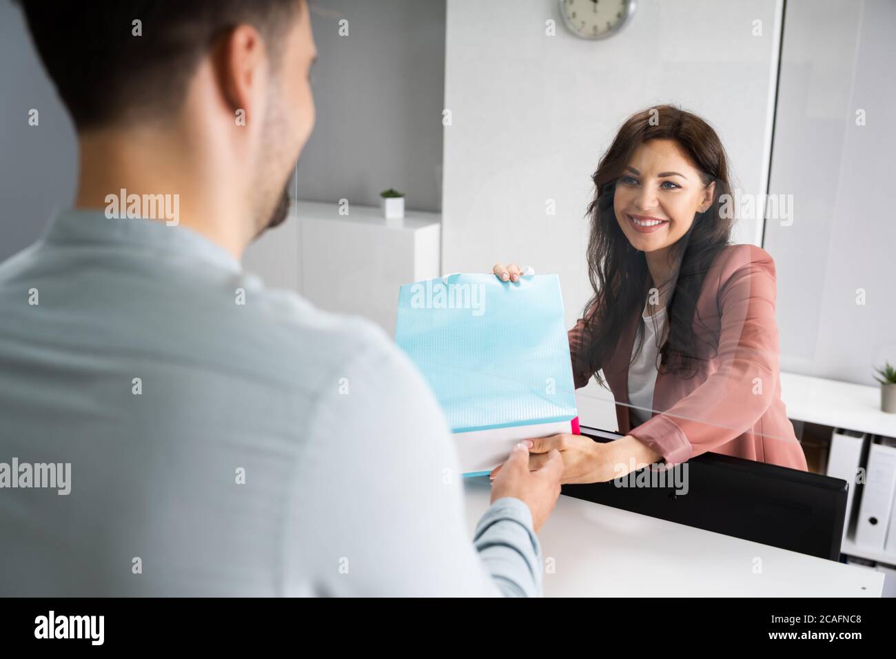 Cassiere nel negozio al dettaglio o negozio al banco che dà la borsa per la spesa Foto Stock