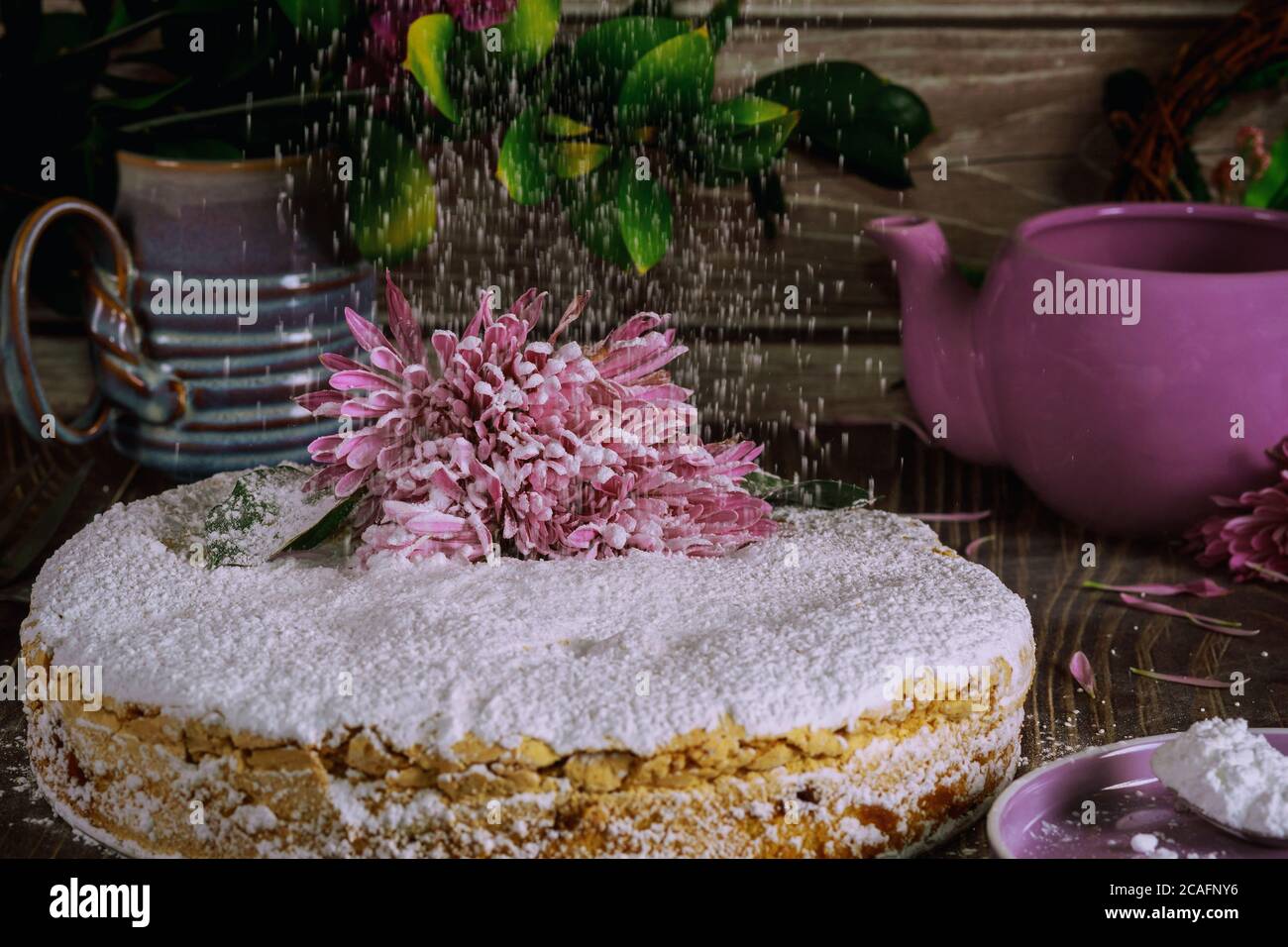 Bella torta con fiori freschi e teiera su sfondo di legno. Foto Stock