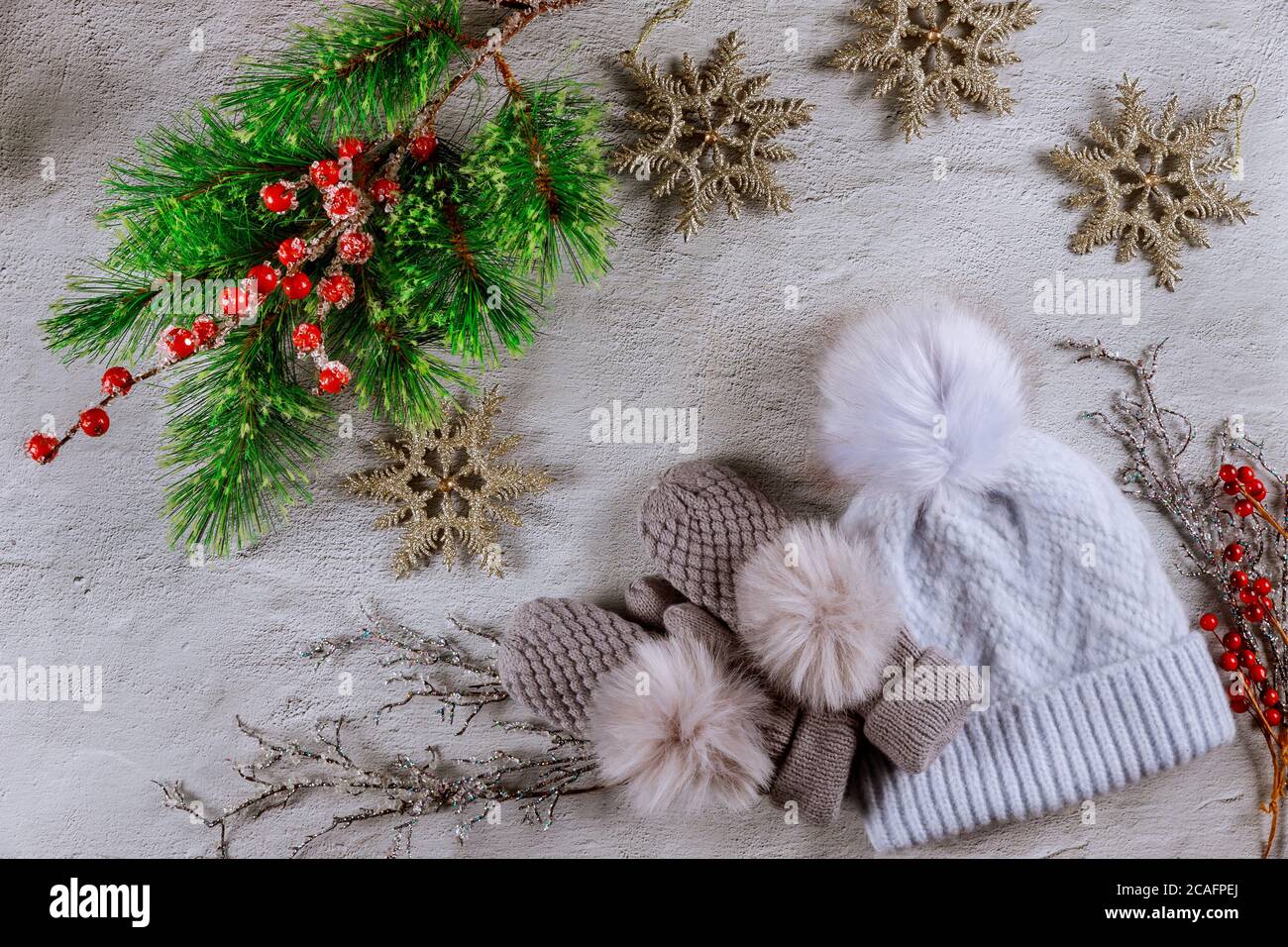 Abete natalizio con bacche rosse, fiocchi di neve e mittene con cappello su sfondo bianco. Foto Stock