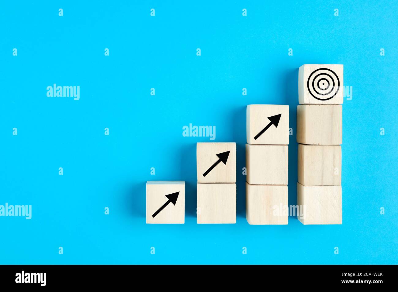 Concetto di crescita economica o commerciale con icone a freccia su legno cubi su sfondo blu Foto Stock