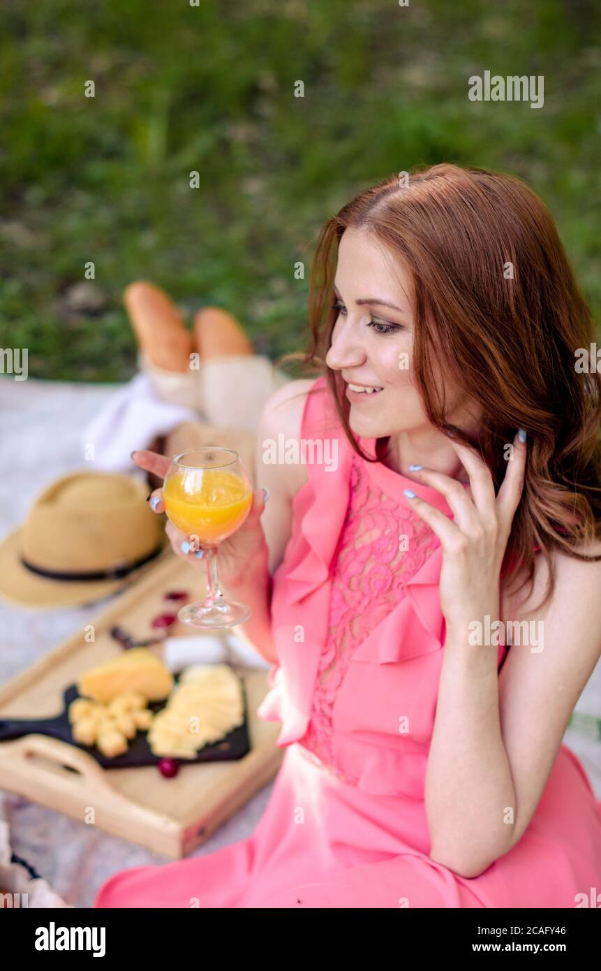 Bella ragazza giovane nel parco che tiene succo, avendo picnic estivo nel parco. Concetto di relax Foto Stock