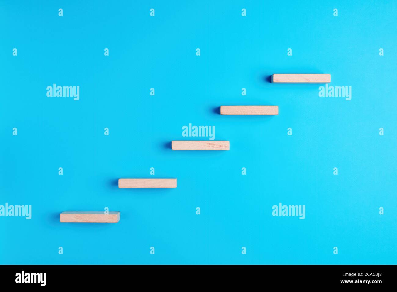 Blocchi di legno che formano una scala su sfondo blu. Scala di successo, promozione o avanzamento. Foto Stock