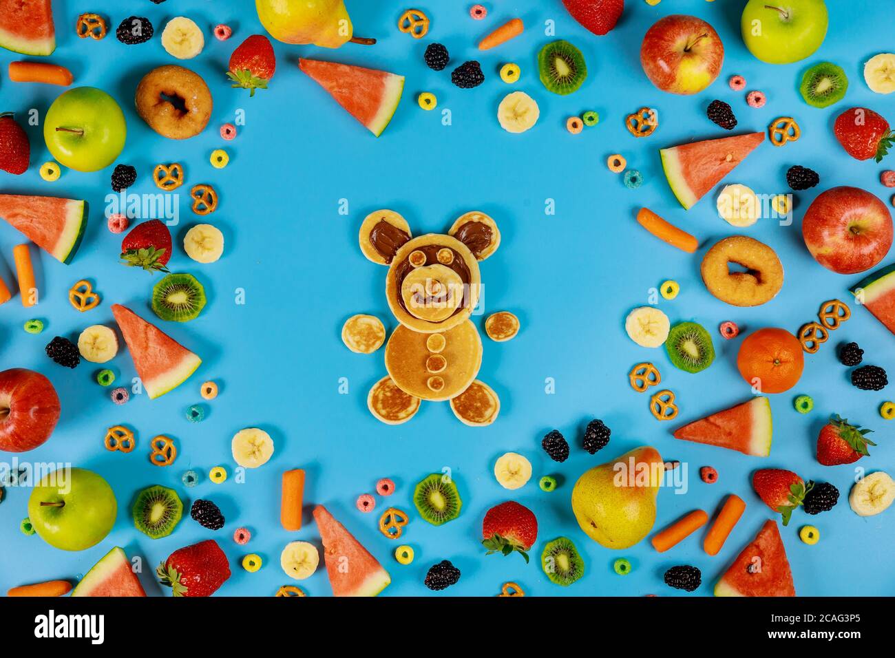 Concetto di cibo sano per i bambini. Frutta e verdura con buffo orso fatto da frittelle. Foto Stock