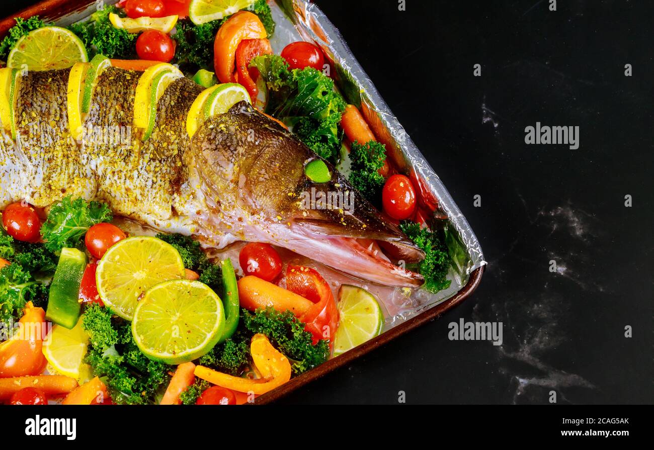 Un luccio fresco con verdure colorate e spezie sulla teglia da forno Foto Stock