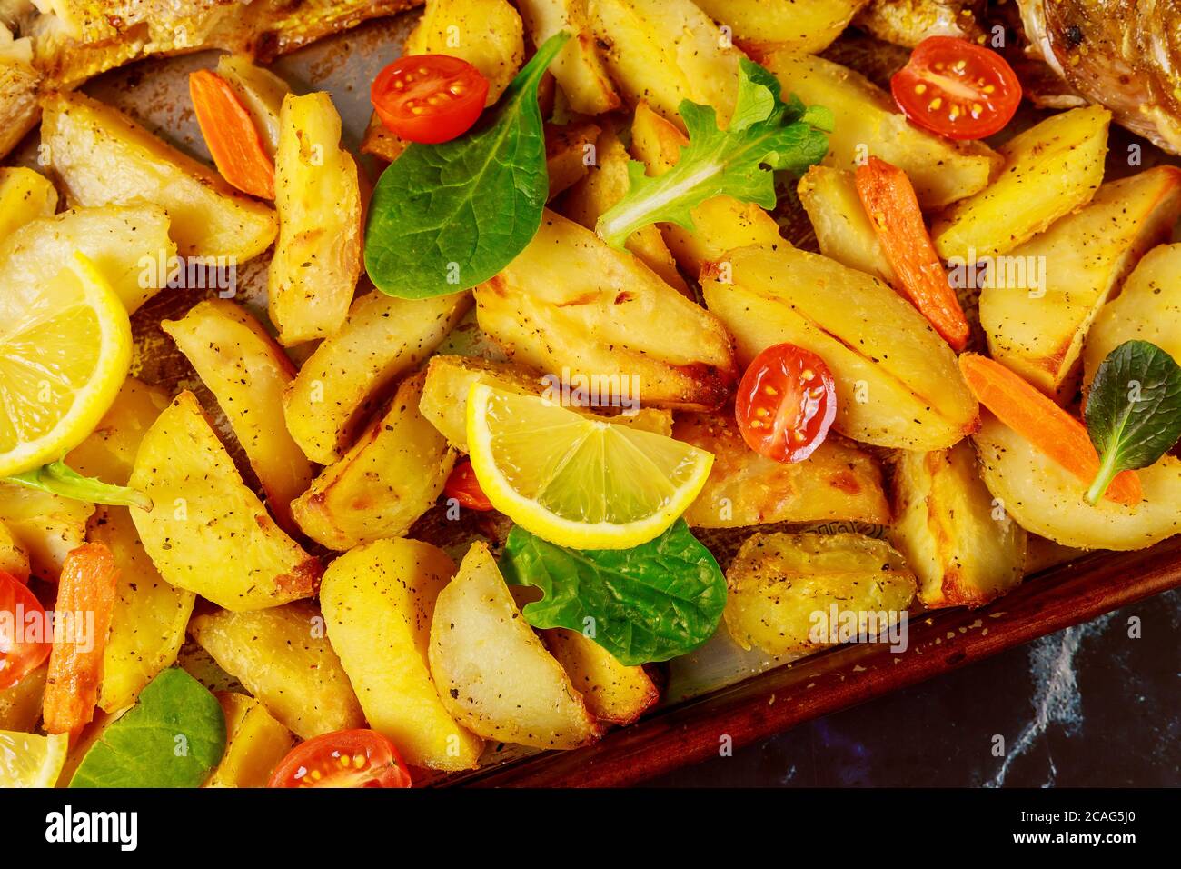 Spicchi di patate al forno con pomodoro fresco e limone. Primo piano. Foto Stock