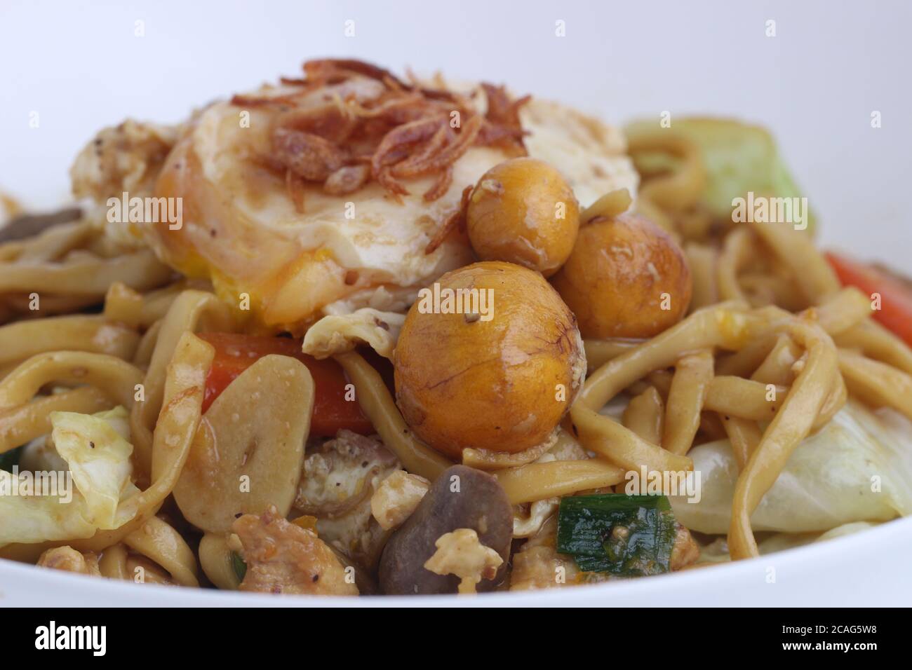 Bakmie Jawa Indonesian cibo di strada tradizionale fritto Noodle con uova di uritano isolato su sfondo bianco. Foto Stock