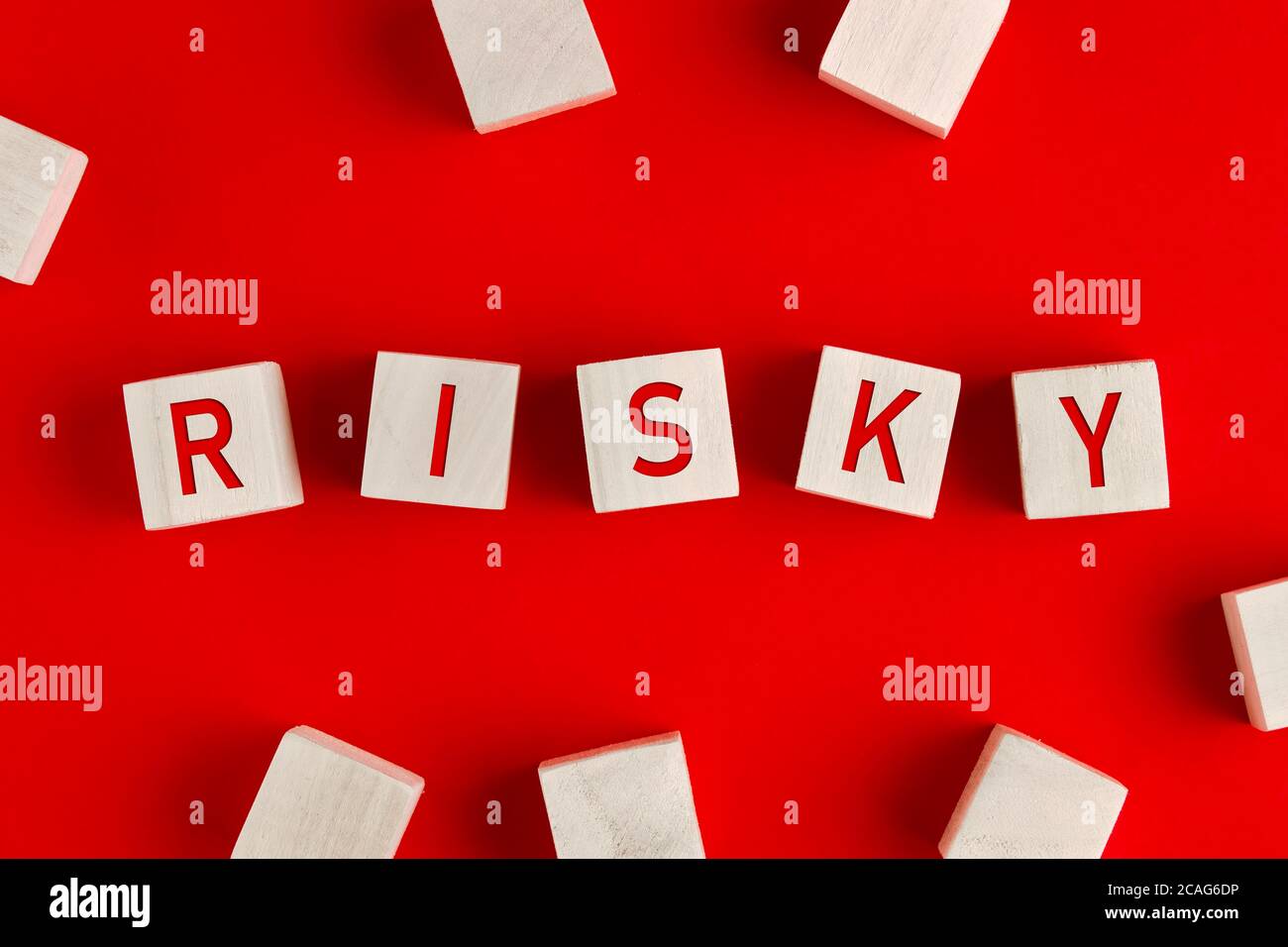 La parola rischioso scritto su blocchi di legno su sfondo rosso. Concetto di gestione del rischio o di valutazione e di processo decisionale in un'impresa incerta Foto Stock