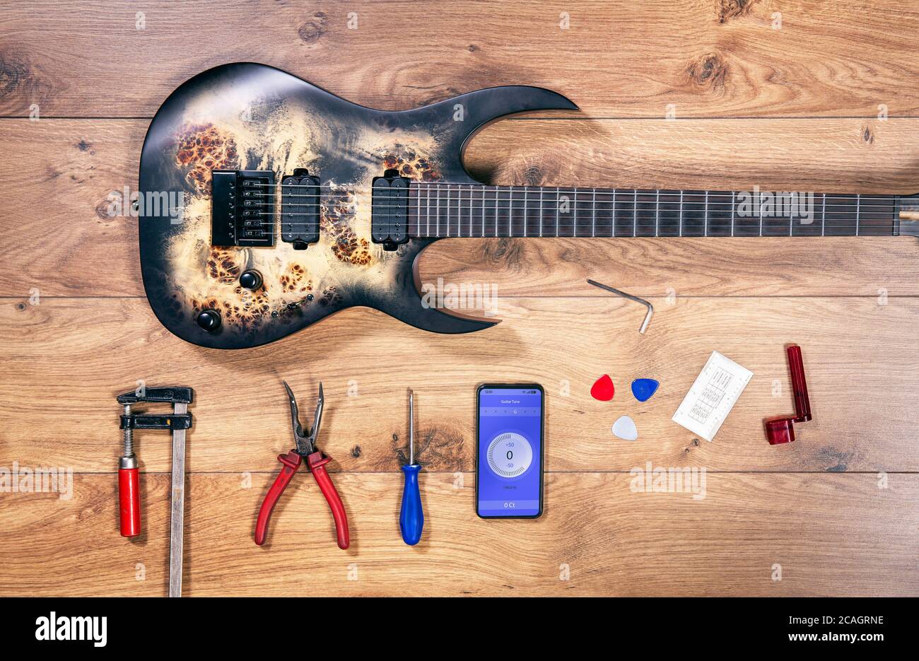 Vista dall'alto più lustra con chitarra e strumenti moderni. Scrivania artigianale in legno con vista piatta e chitarra elettrica in metallo rock. Foto Stock