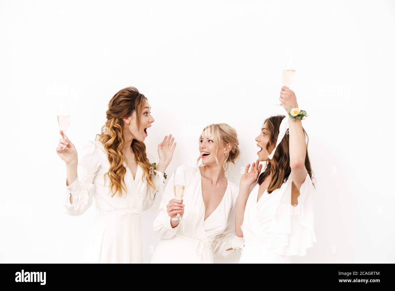 Foto di giovani bridesmaid che ballano e bevono champagne isolato su pareti bianche Foto Stock
