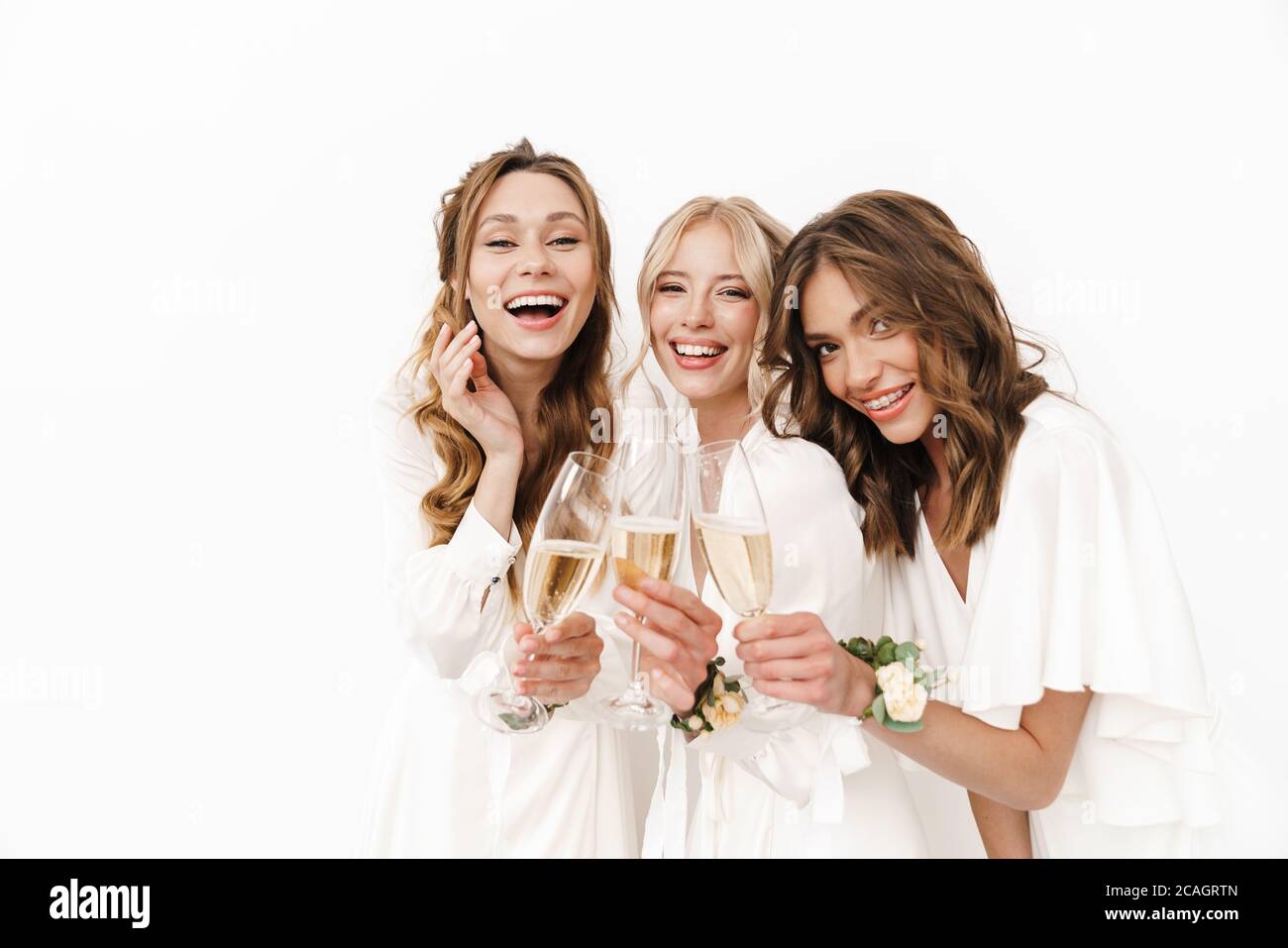 Foto di gioiose e belle bridesmaid che ridono e bevono champagne isolato su pareti bianche Foto Stock